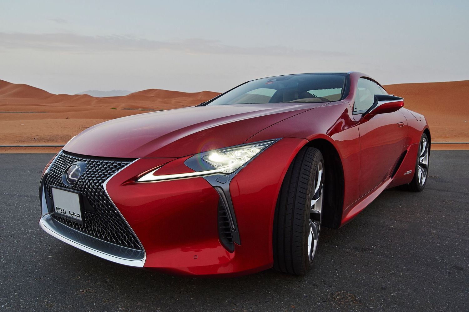 Sleek red Lexus concept car photographed against desert landscape during sunset.
