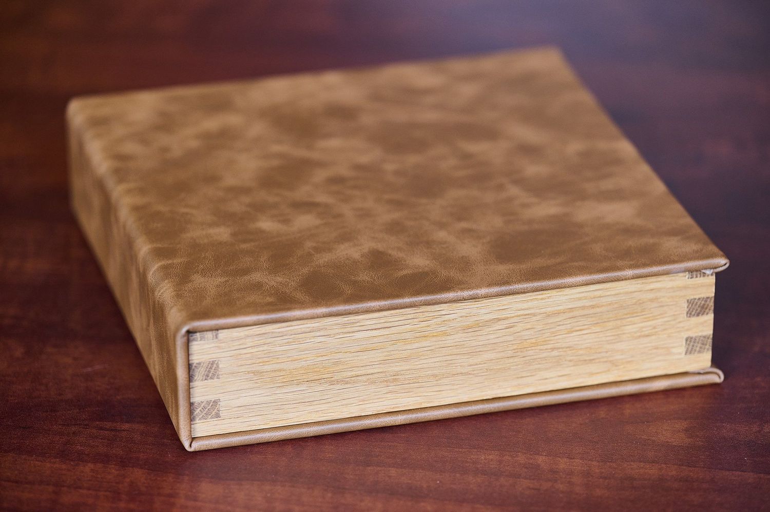 A series of seven photos showing a book cover being progressively folded and closed on a dark wooden surface.