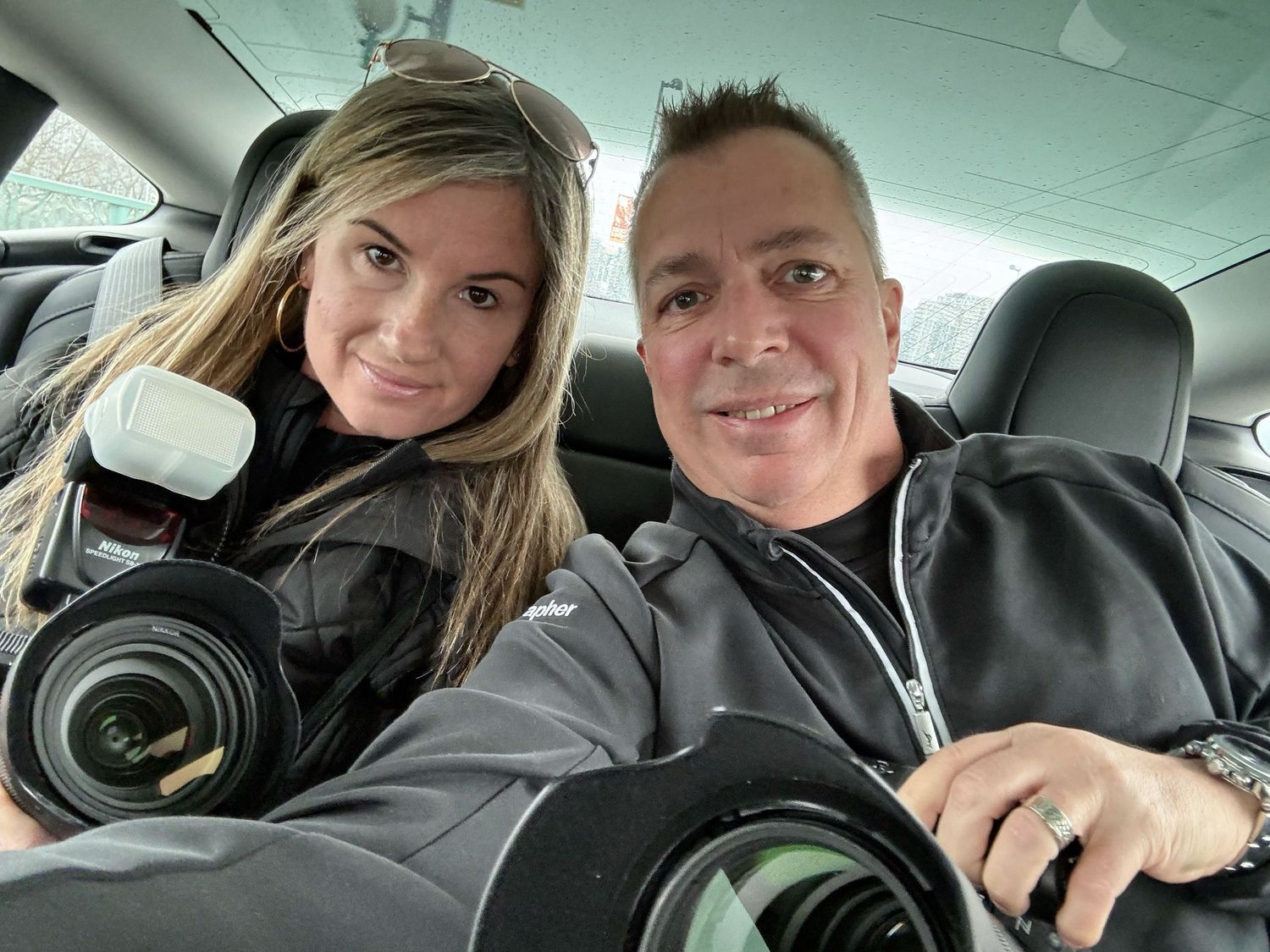 Two people taking a selfie together in a car interior with smiling expressions.