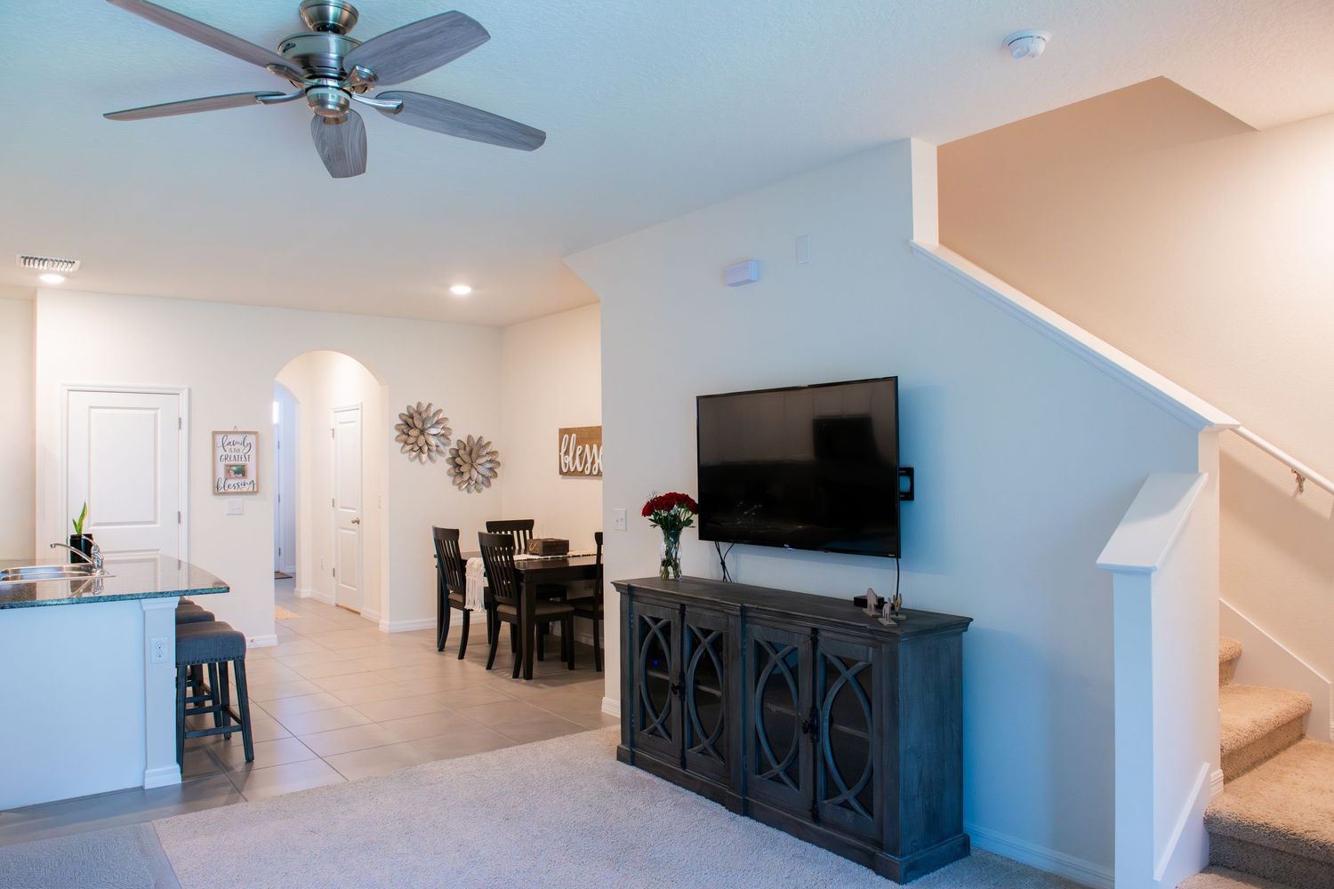 Modern open concept living room with light blue walls, ceiling fan, and mounted TV in a newly renovated space.