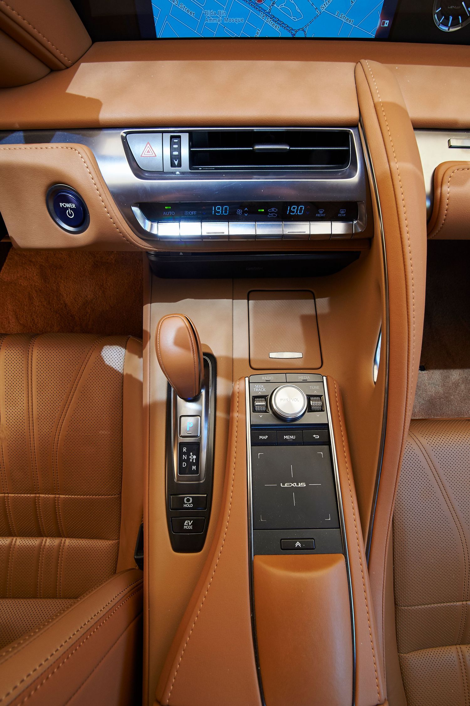 Close-up of a Lexus center console with tan leather trim and climate controls.