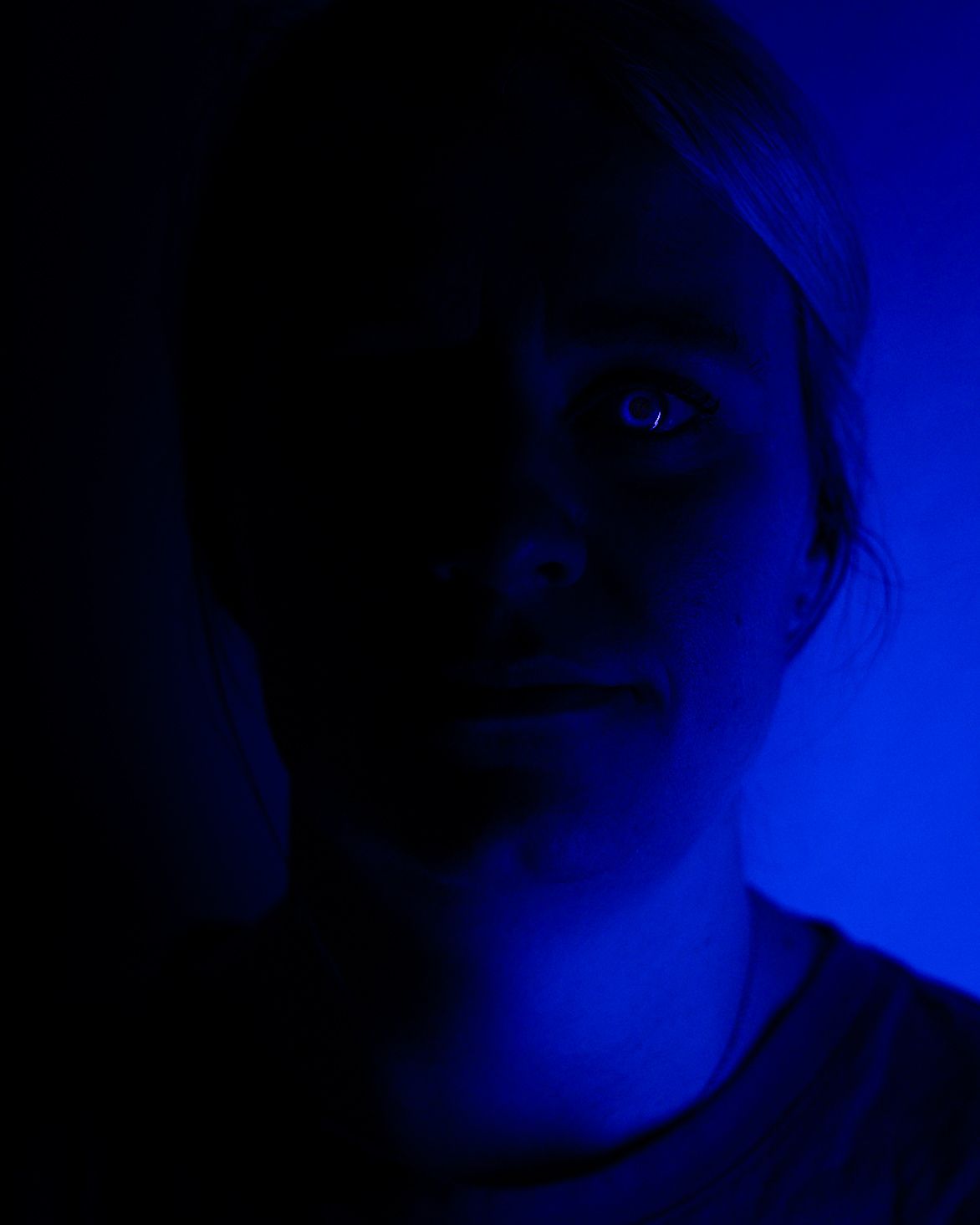 Dramatic blue-lit portrait sequence showing shadowy angles in dark ambient lighting.