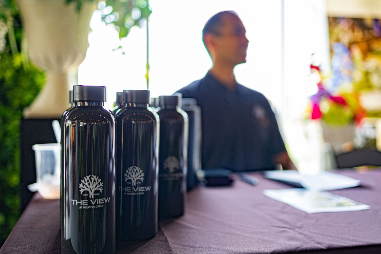 Black branded water bottles with The View logo displayed on a table at an outdoor event.