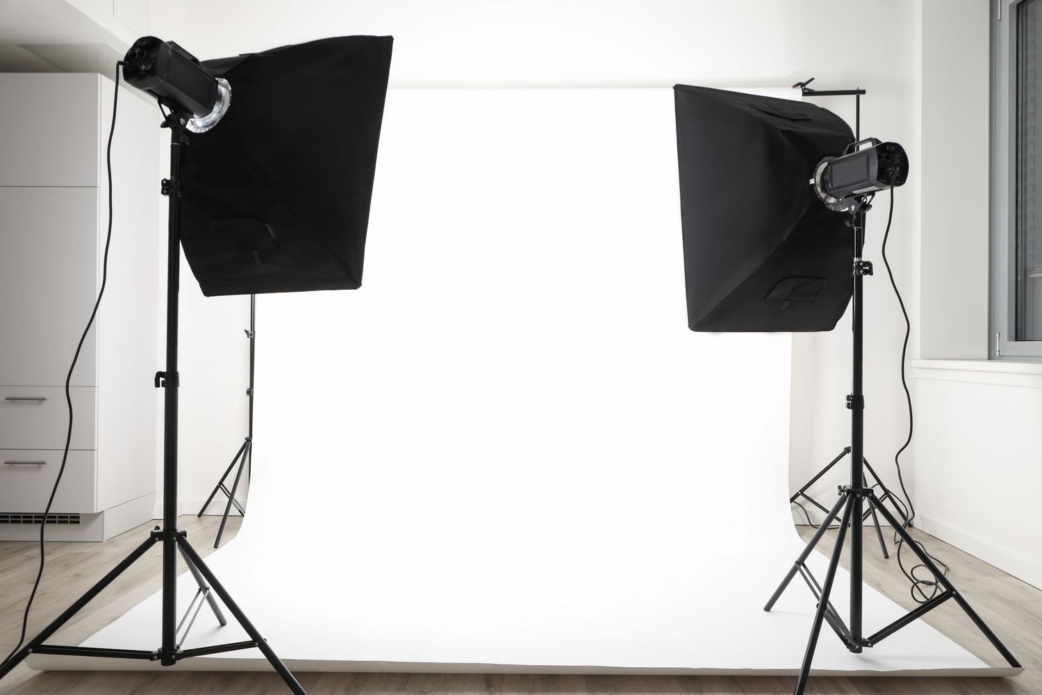 Professional photo studio setup with two softbox lights on stands and a white backdrop for photography sessions.