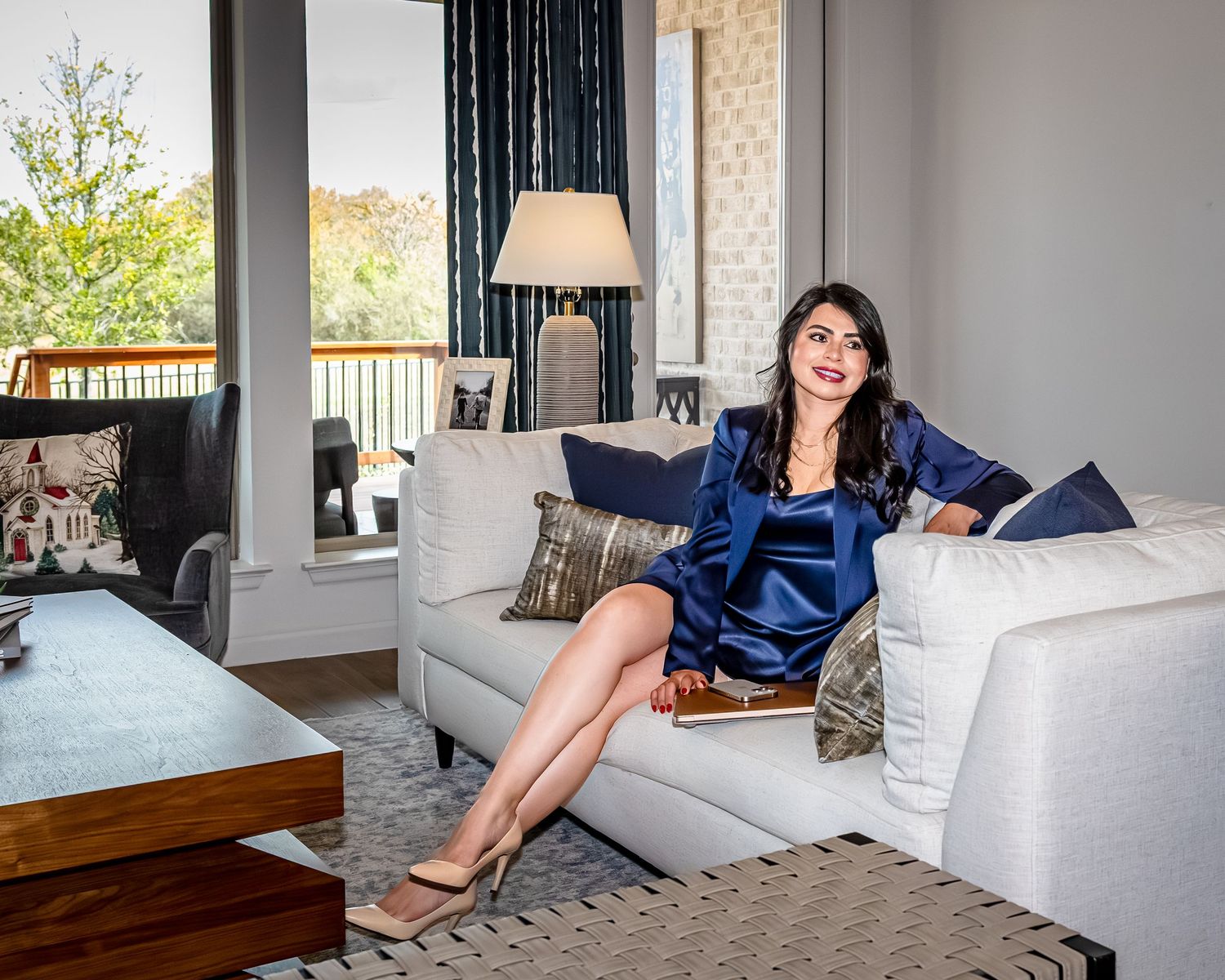 Person in navy blue loungewear relaxes on a plush gray sectional sofa in a modern living room setting.