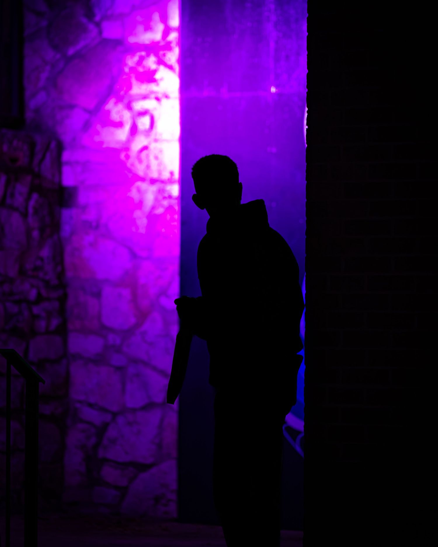 Silhouette against purple illuminated wall creating dramatic atmosphere.
