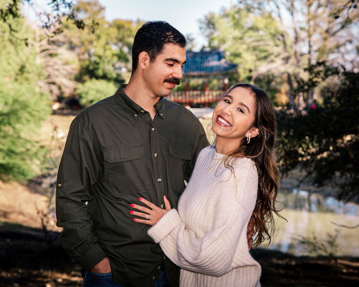 A couple shares a joyful moment together outdoors during an autumn engagement photoshoot.
