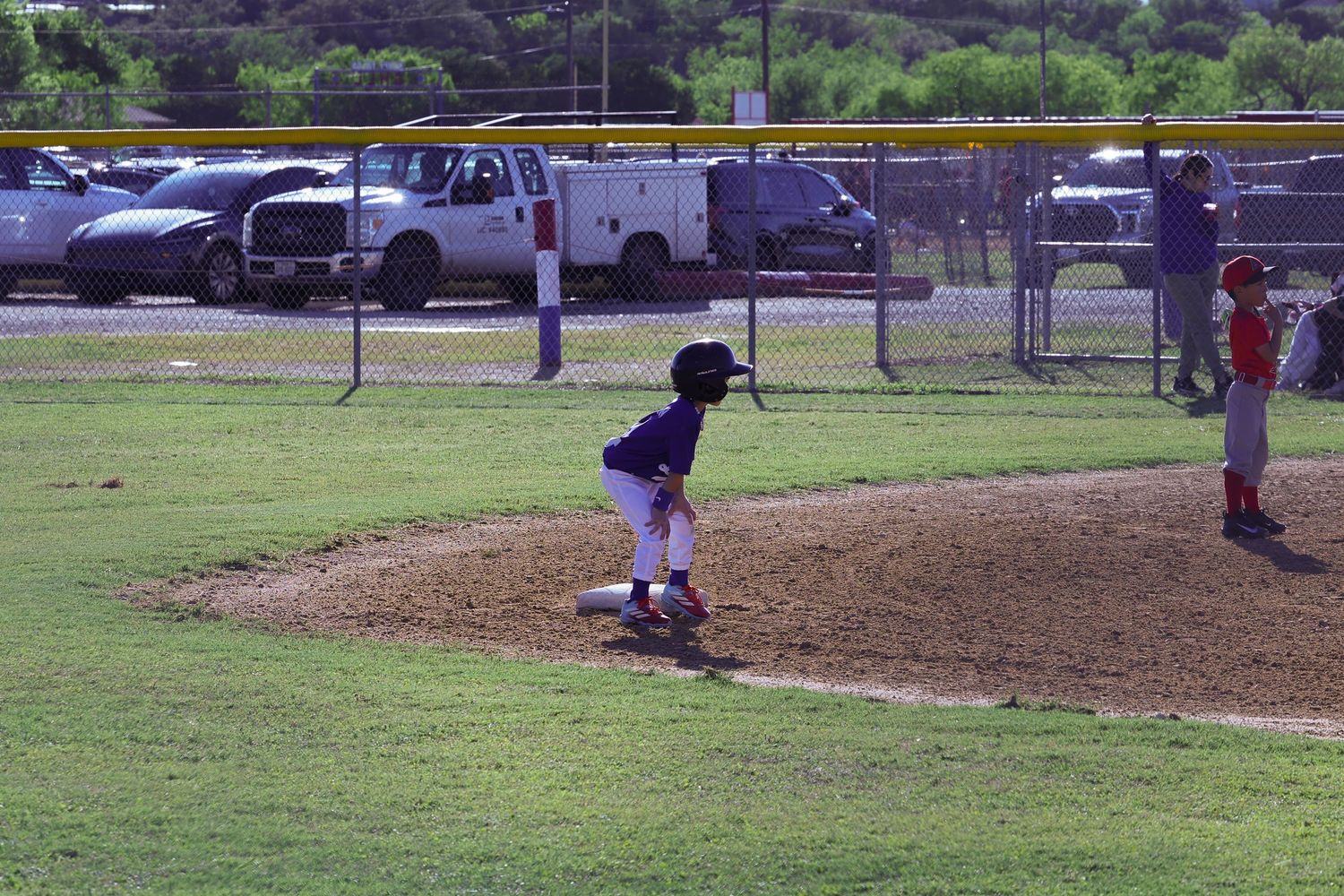 Young baseball player pitching on a youth league mound during a daytime game at a green grass field.