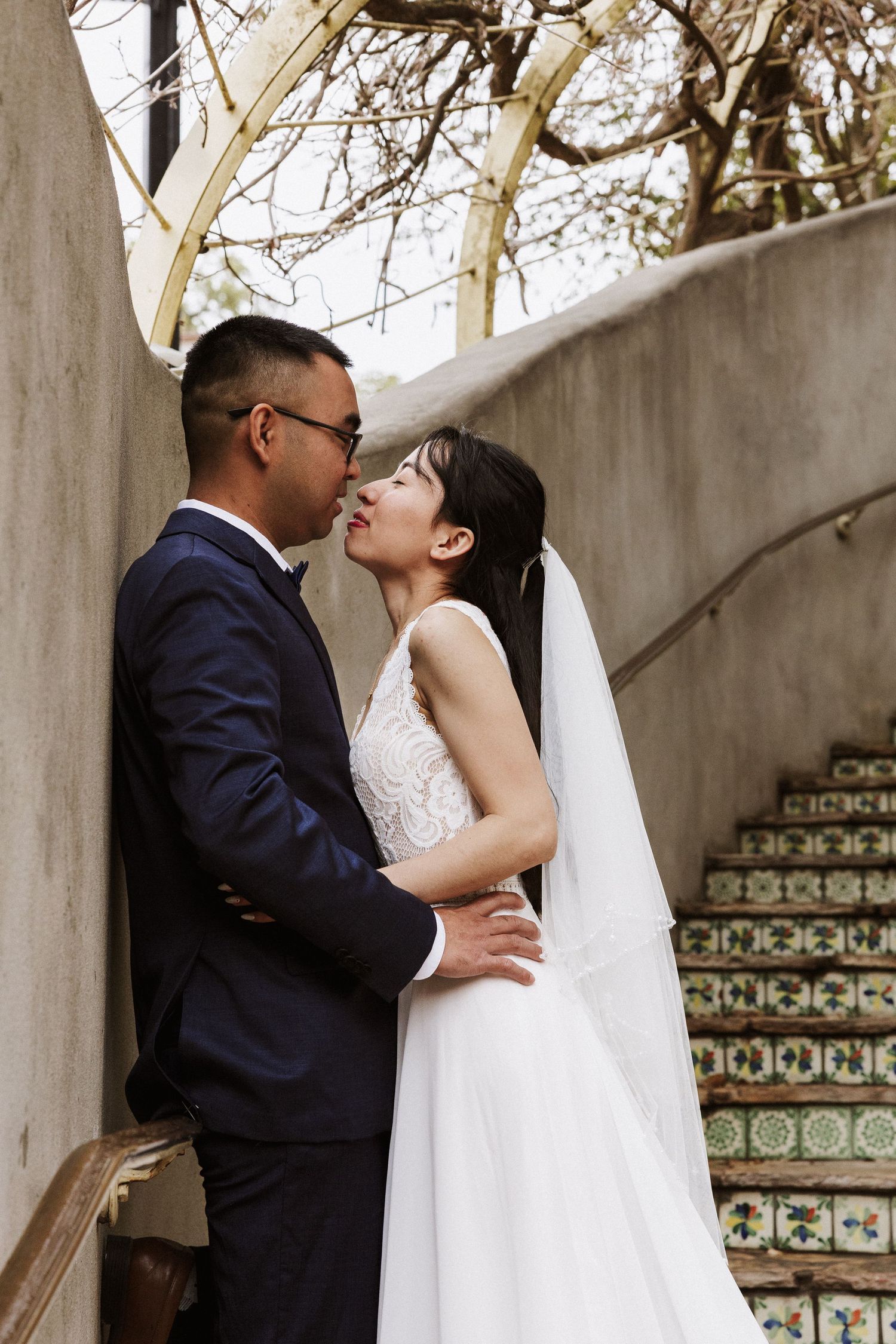 A romantic wedding couple shares intimate kisses in a series of photos under decorative arches with tiled details.
