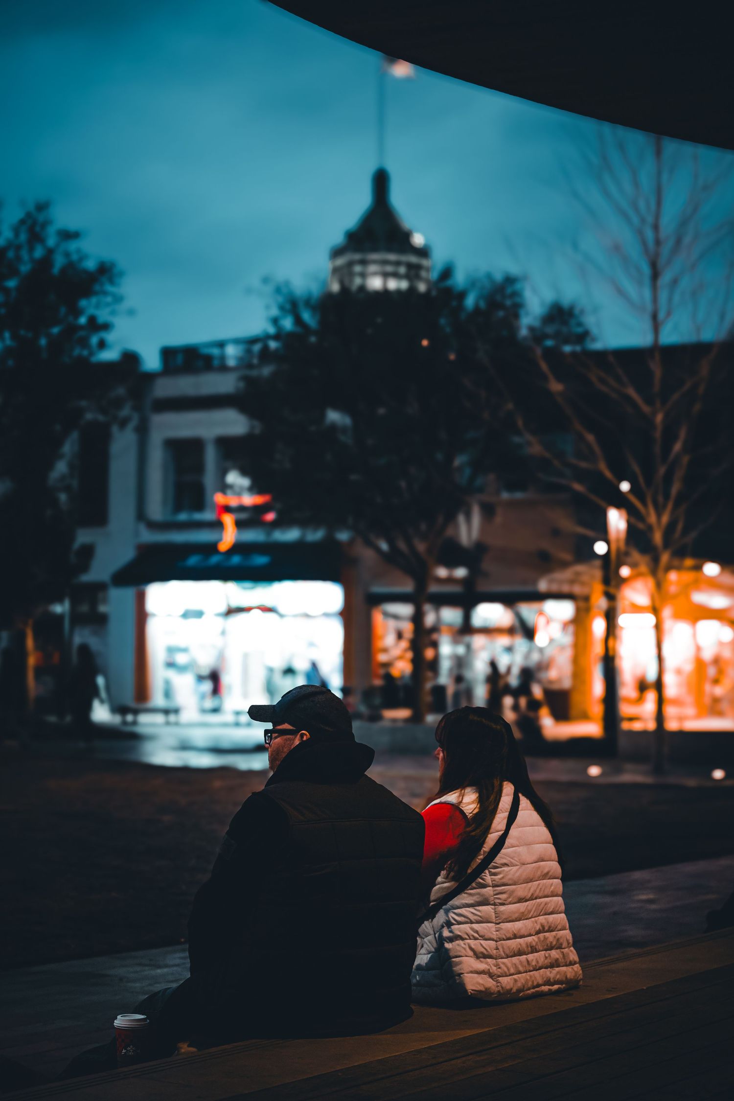 Small town street at twilight with glowing storefronts and buildings.