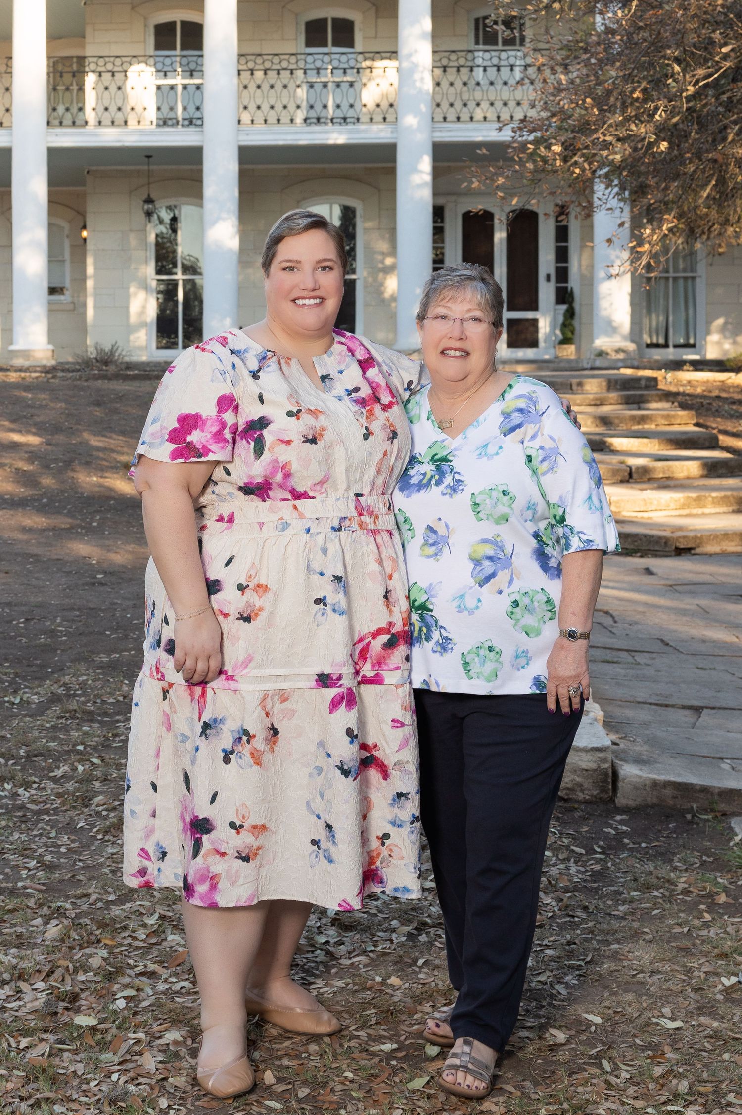 Two older women standing together in front of a historic building.