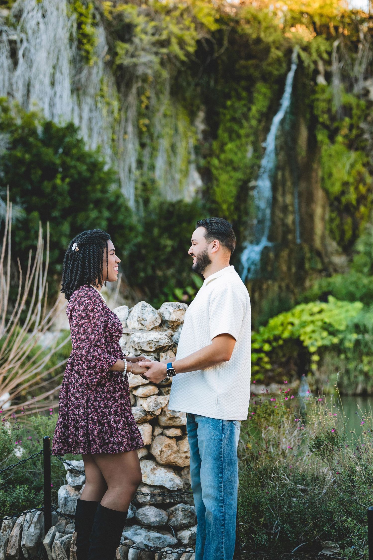 Couple shares tender moment near rustic stone wall with Spanish moss and natural garden landscaping.