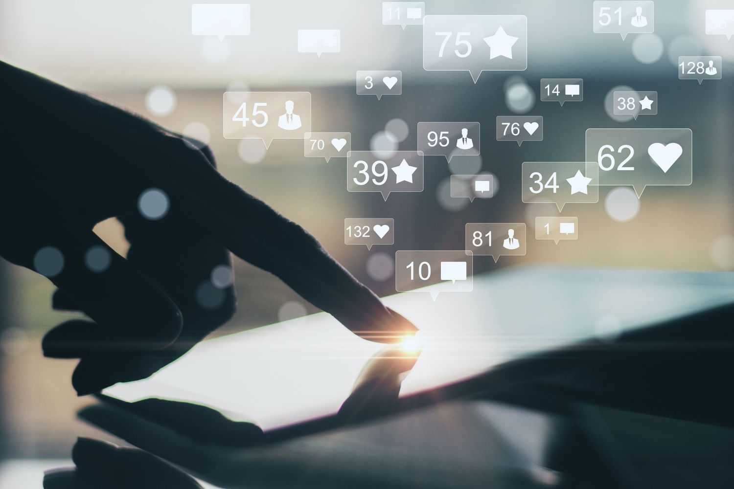 Hands touching a tablet with social media icons, likes, and notifications floating above the screen.