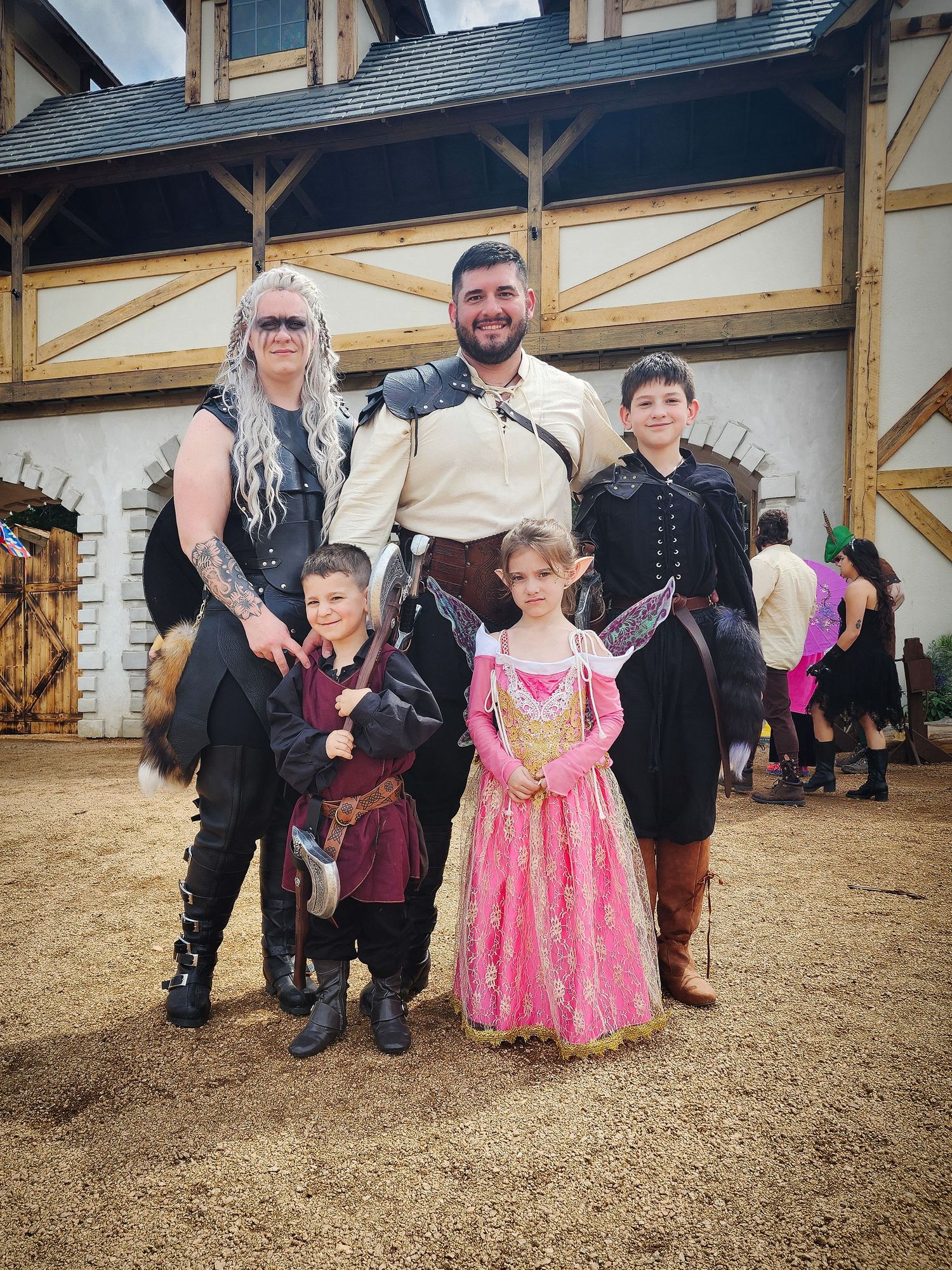 A group of people stand together on a hay-covered floor in a rustic barn setting.