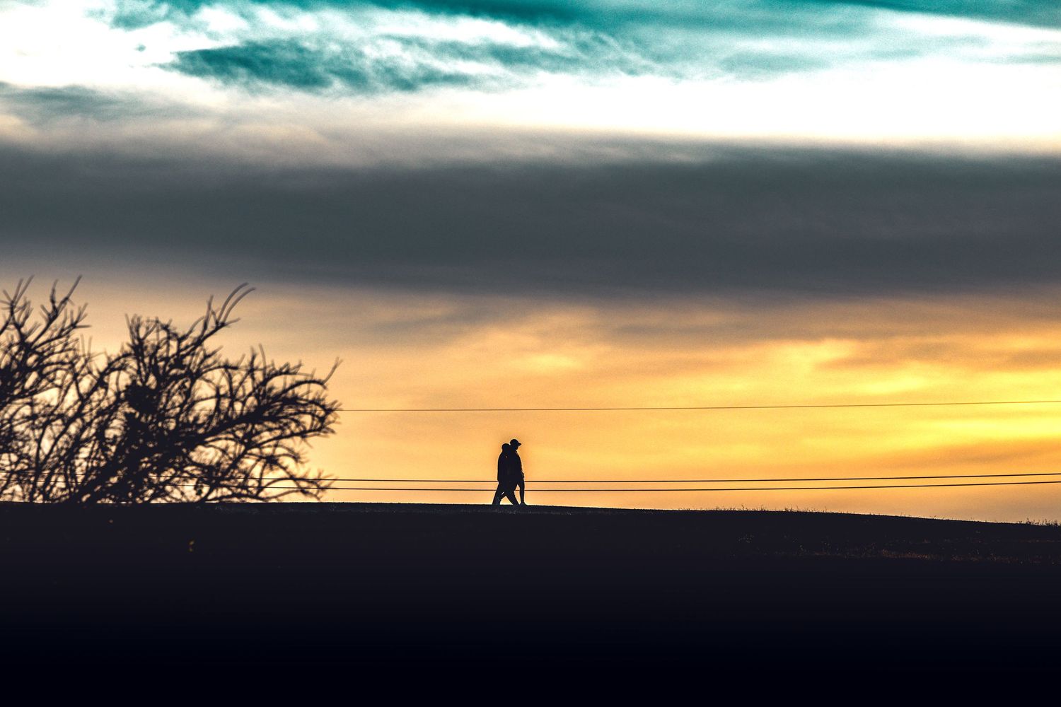Dramatic sunset silhouettes against a vibrant orange and turquoise sky on the horizon.