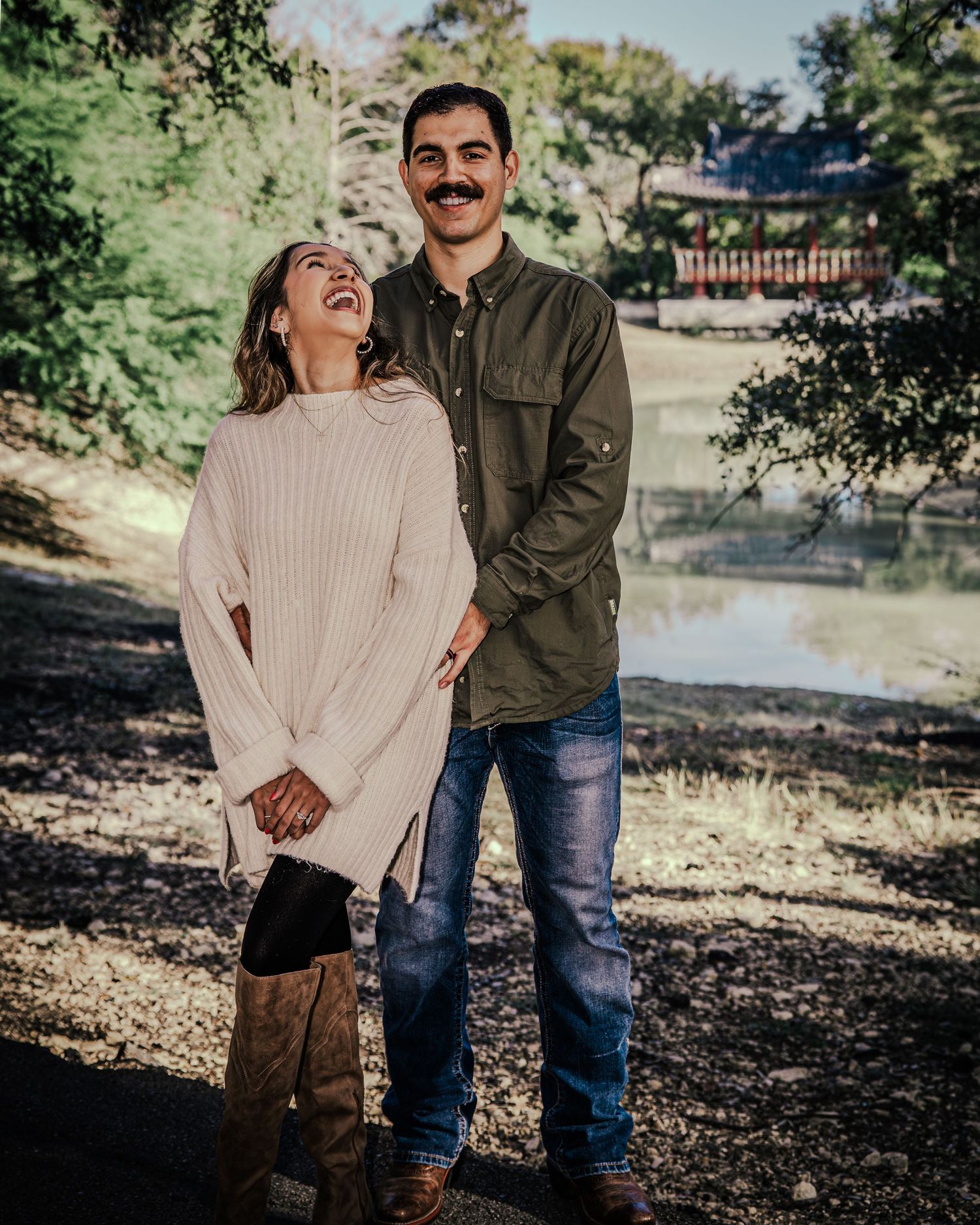 A couple shares a romantic moment together in a park setting with natural lighting and autumn scenery.