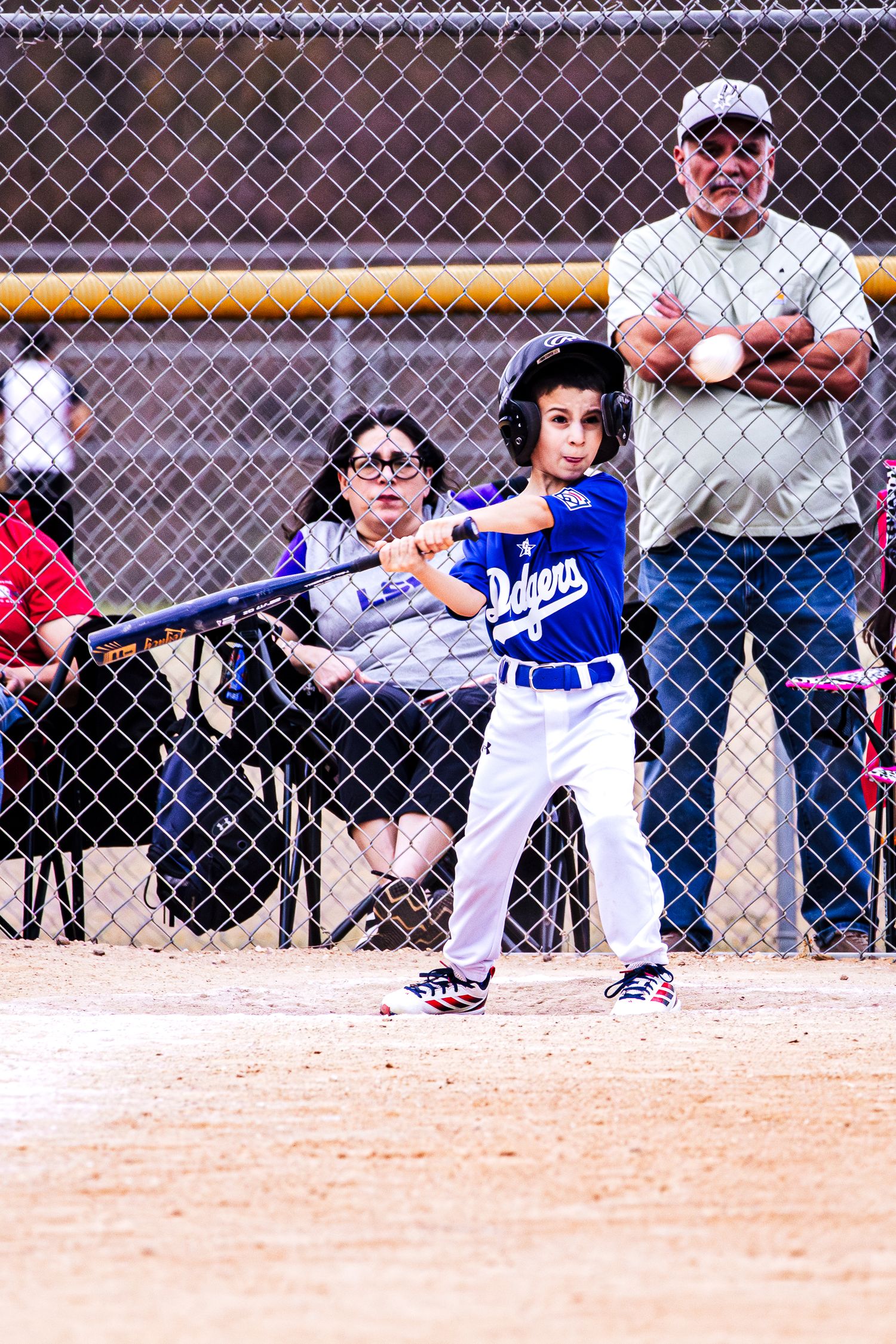 Young Dodgers baseball player in batting stance at home plate during little league game.