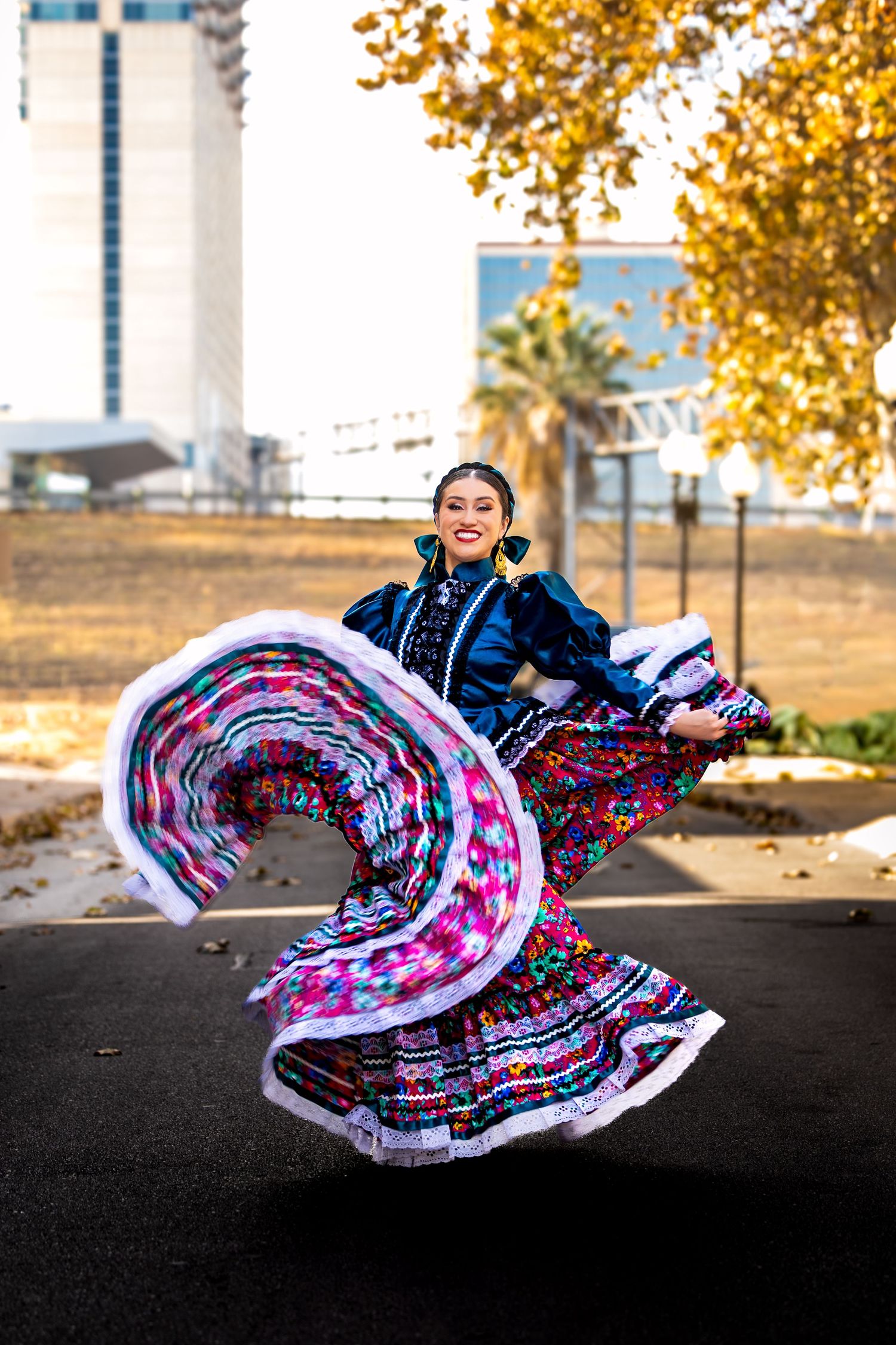 A woman in a colorful traditional Mexican folkloric dress twirls outdoors, her vibrant skirt fanning out beautifully.