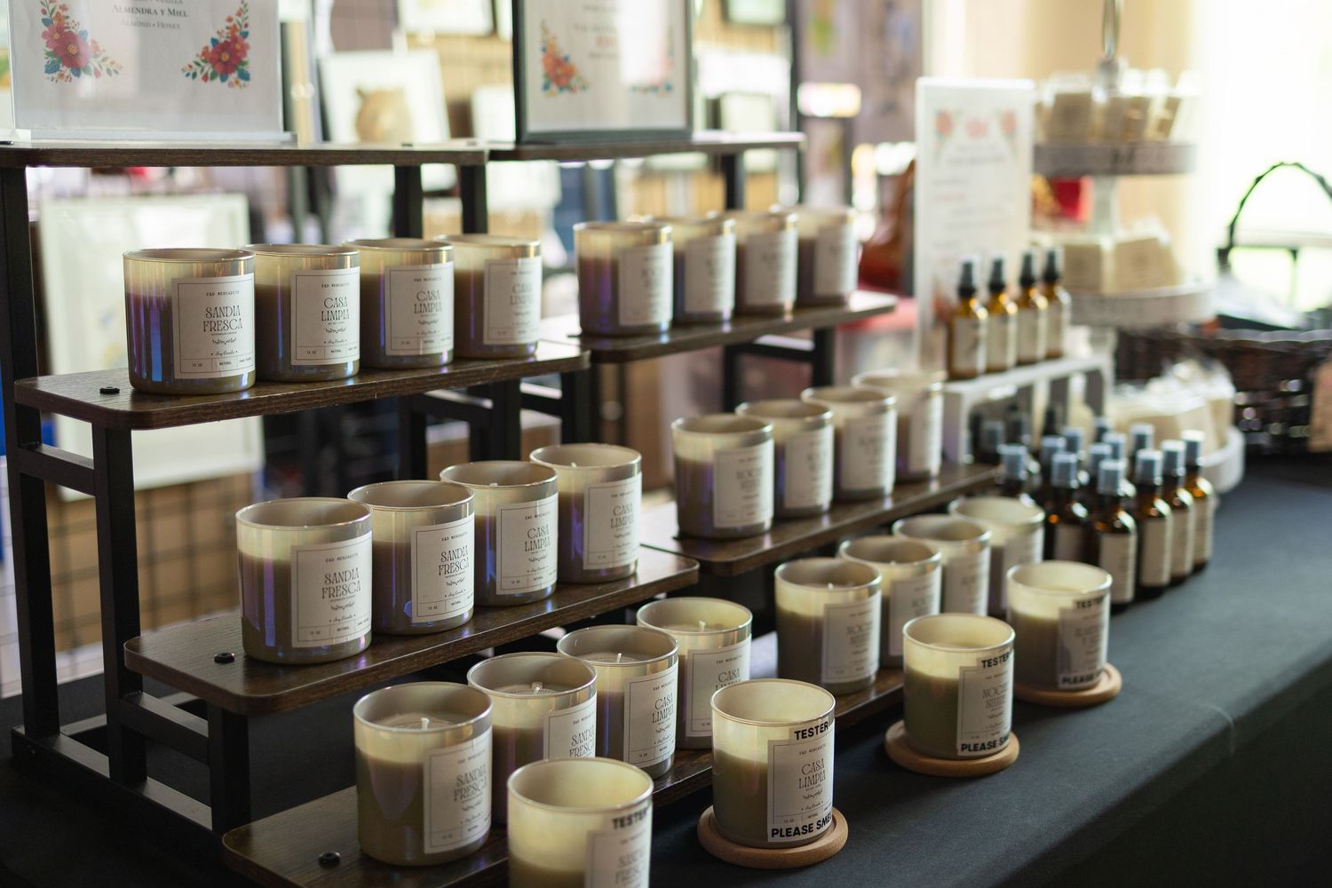 Rows of white scented candles displayed on black metal shelves in a boutique shop setting.