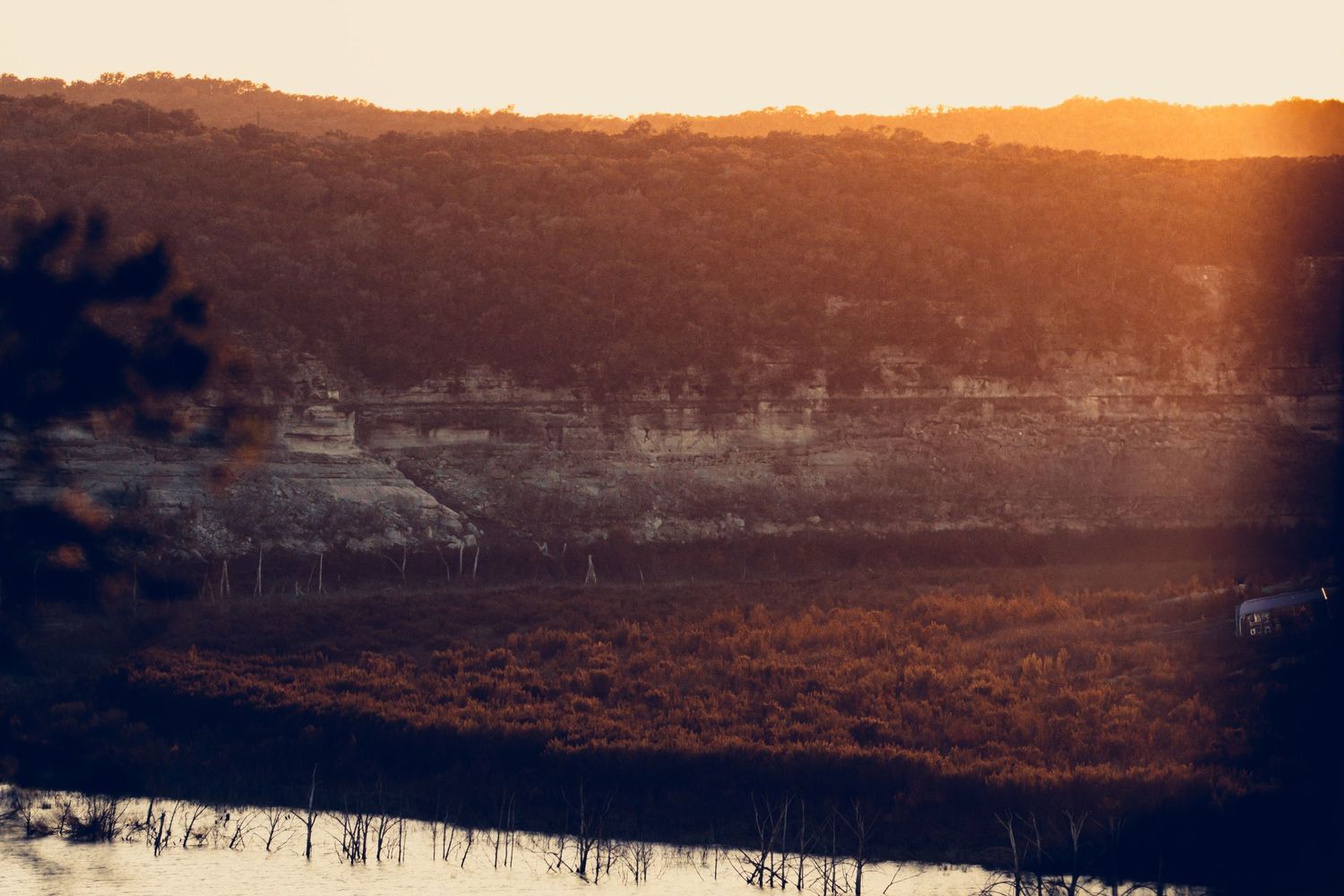 Panoramic sunset view over a tranquil lake with golden sky reflecting on the water surface.