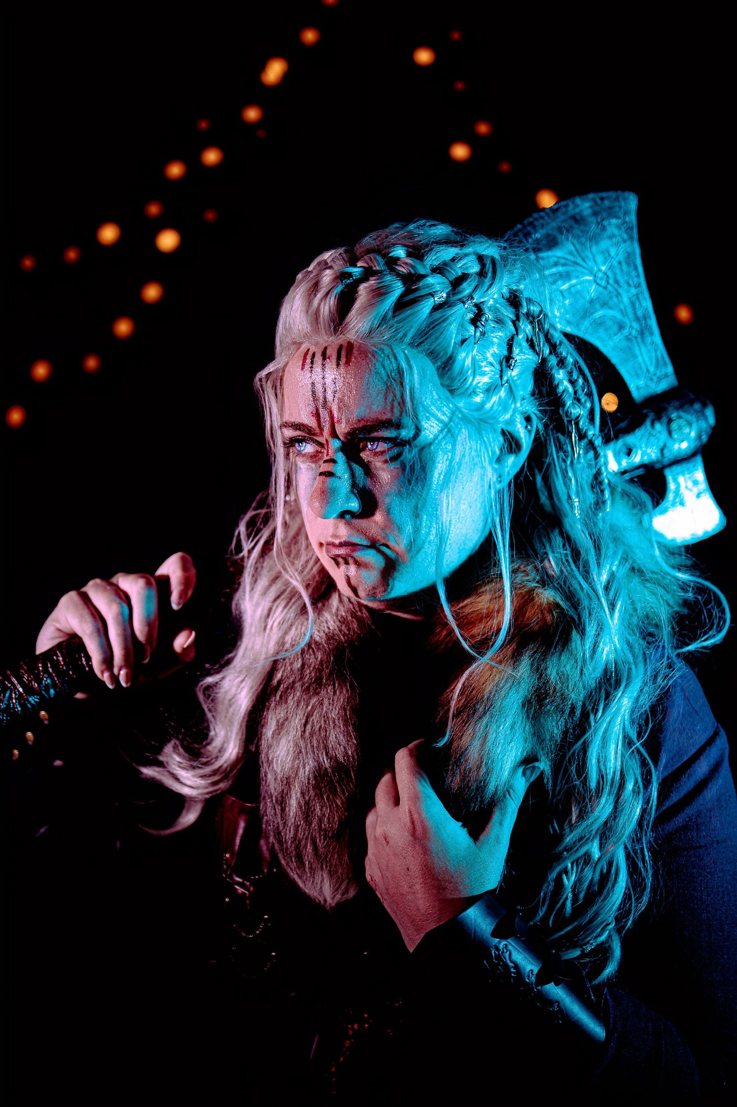Viking warrior woman with braided blonde hair, battle axe, and dramatic blue lighting against dark background.