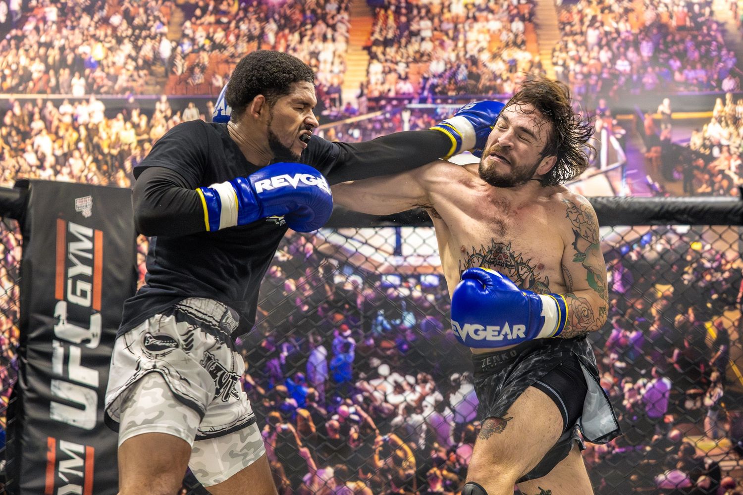 Two MMA fighters exchange punches in a UFC gym ring during an intense match before a packed crowd.