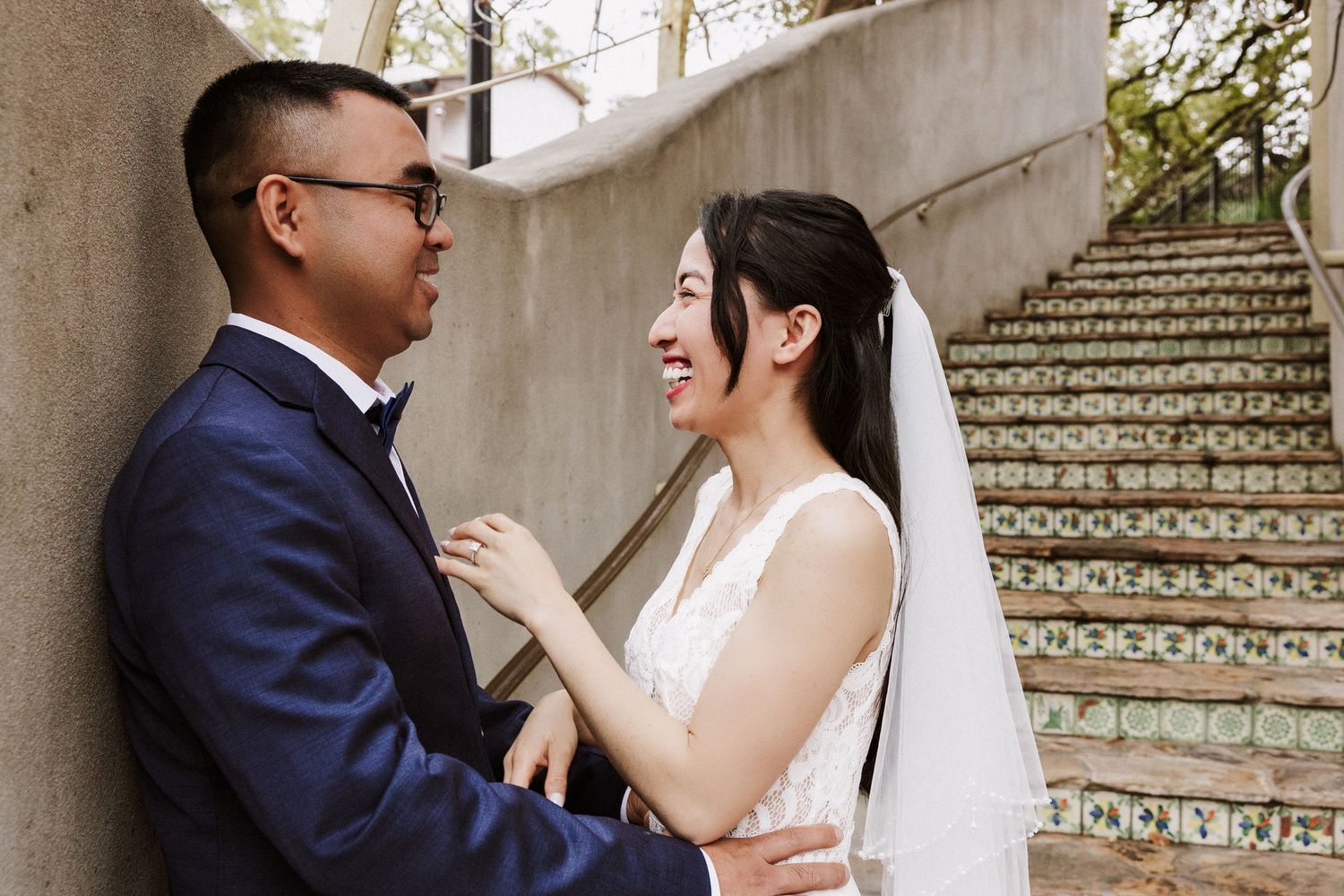 A bride and groom share intimate moments on an ornate outdoor staircase with decorative tile details.