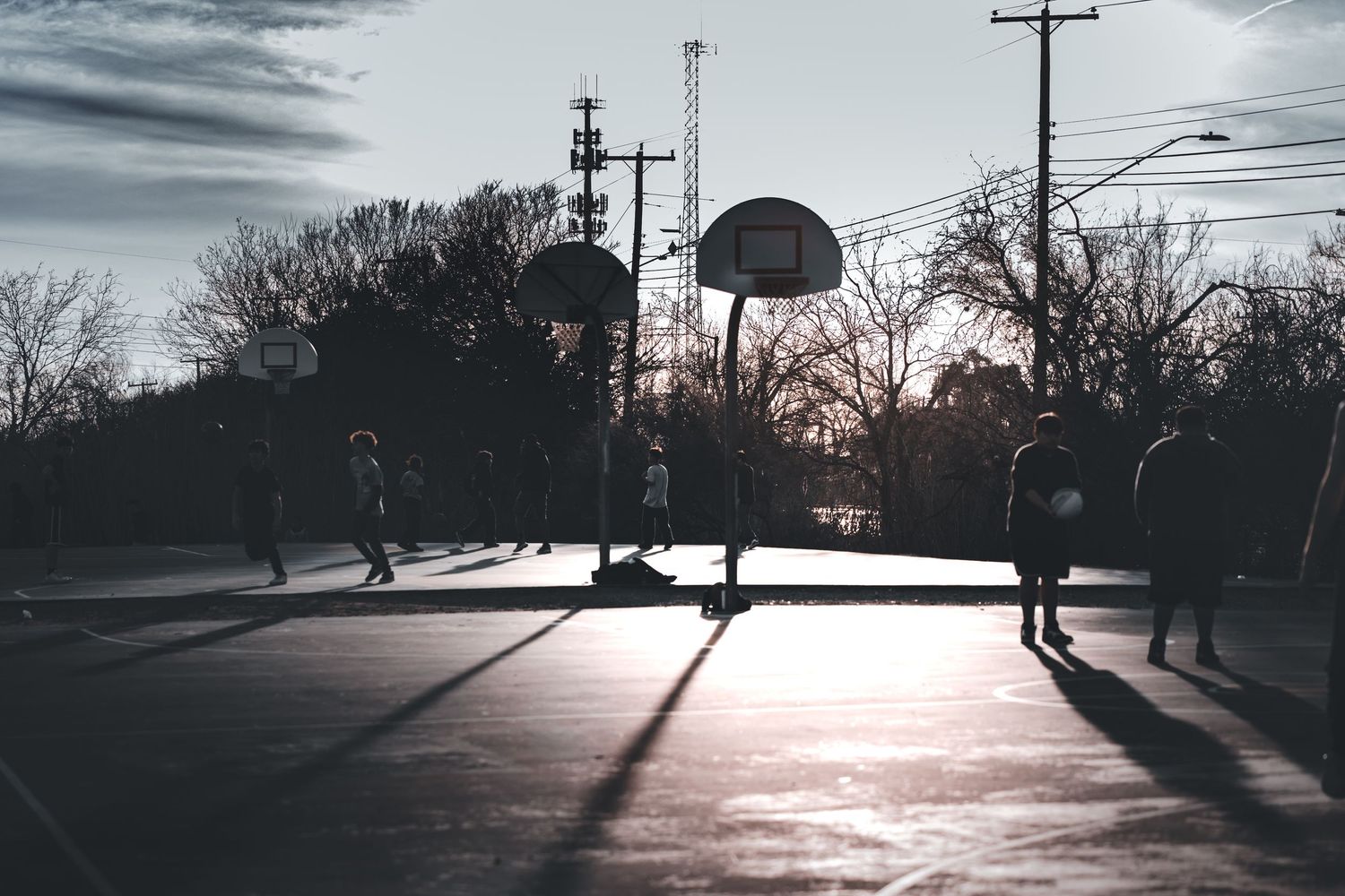 Long shadows cast across empty street during sunset with utility poles silhouetted.