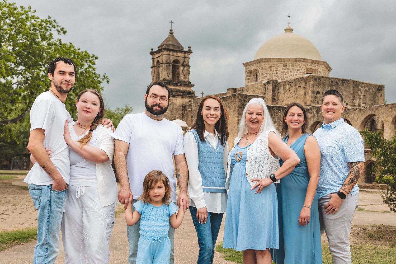 Family group photo in front of historic San Jose Mission in San Antonio, Texas on a cloudy day.