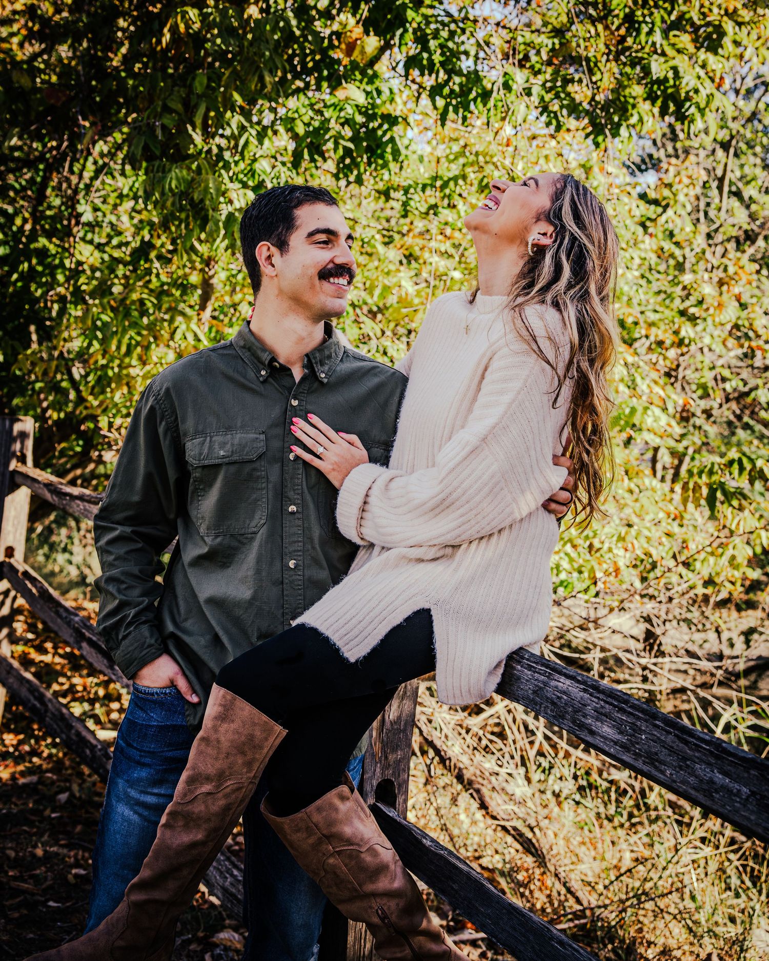 Couple sitting together on wooden steps surrounded by autumn foliage in a romantic outdoor setting.