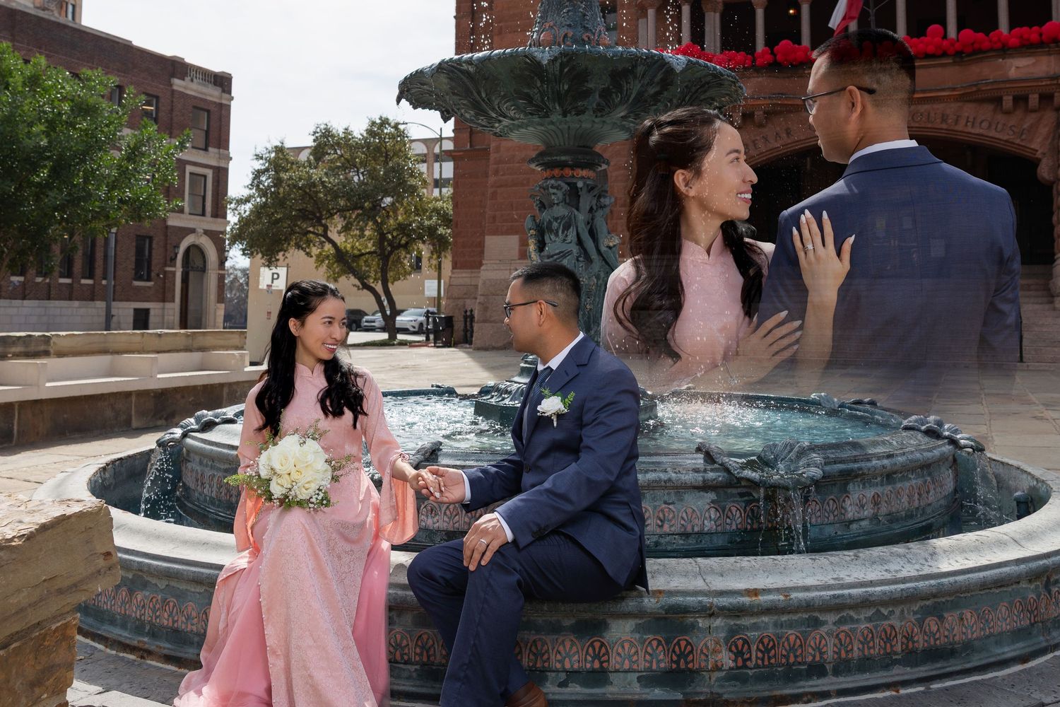 A couple shares a romantic moment in front of a fountain during what appears to be an engagement photo session.