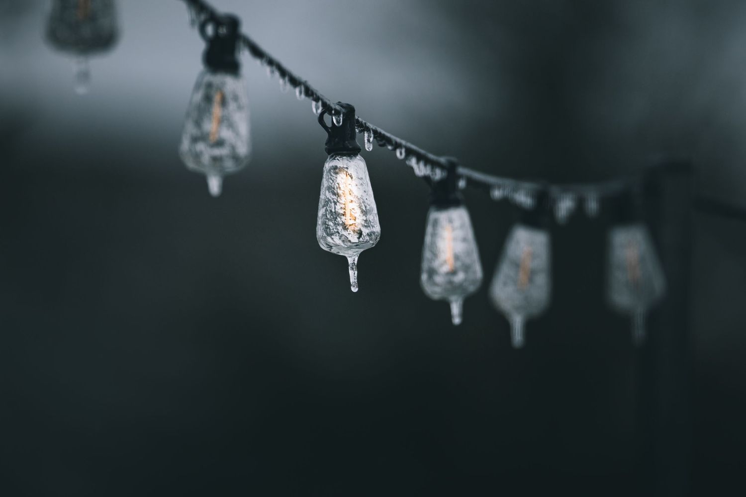 Frosted glass ornaments hanging on string with bokeh effect in cool tones.