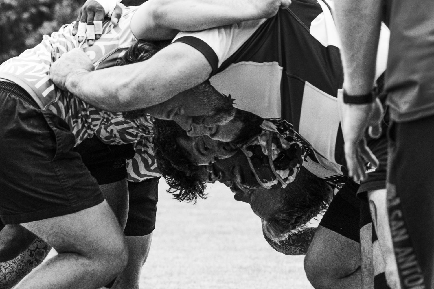 Black and white photo of rugby players engaged in an intense scrum during a match.