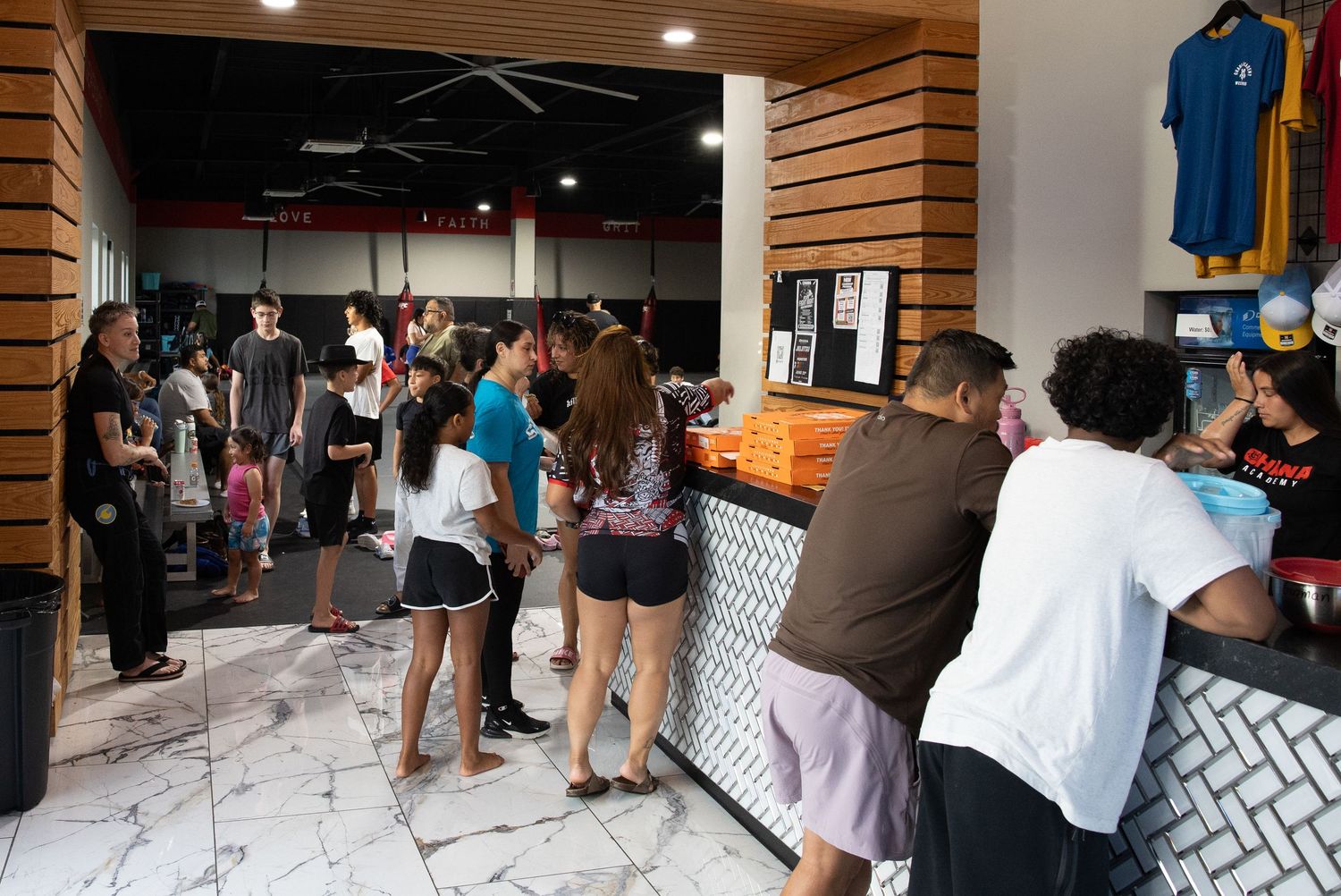 Busy restaurant counter with customers ordering food, marble floors, and merchandise display in modern fast-casual eatery.