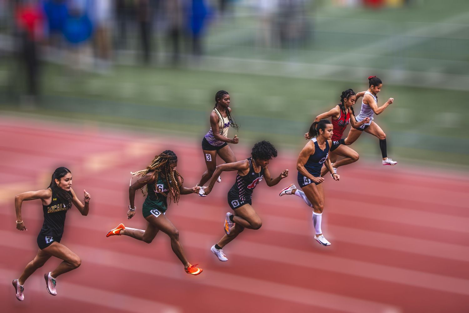 Female sprinters race on an outdoor track with motion blur capturing their speed and athleticism.