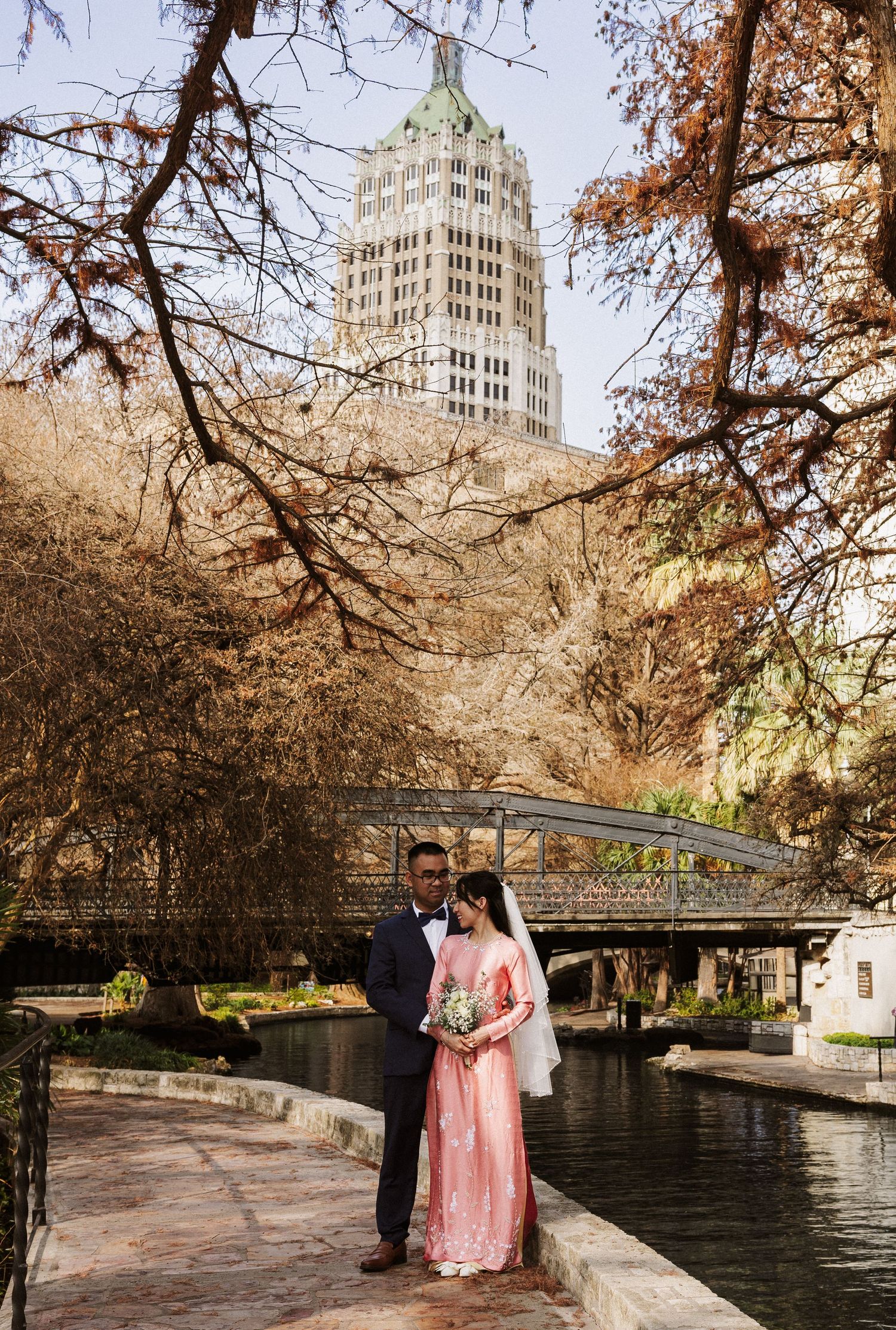 Scenic view of the San Antonio River Walk with autumn trees and historic architecture along the stone pathways.