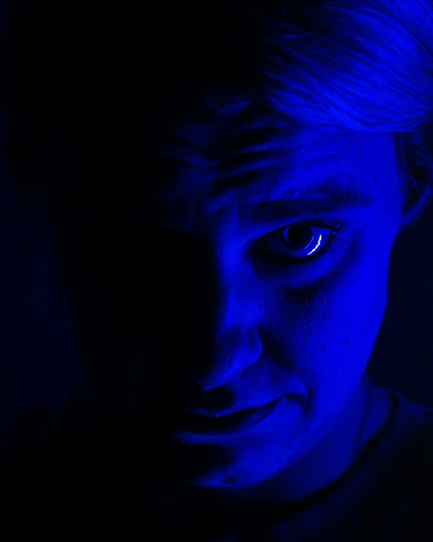 Abstract blue light pattern creates a dark moody atmosphere with glowing curves and shadows against black background.