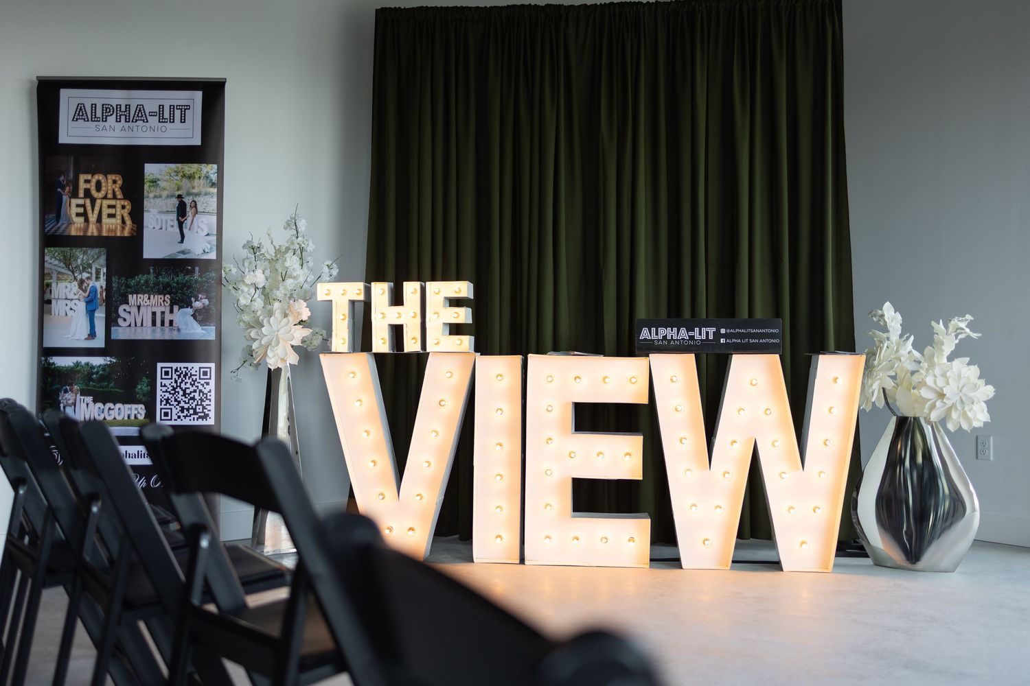 Illuminated marquee letters spelling THE VIEW displayed at an event venue with floral arrangements and Alpha-Lit branding.