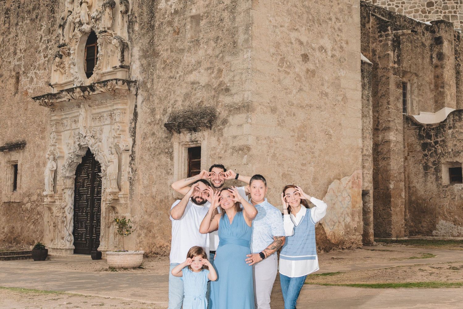 Family group posing playfully in front of an ancient stone church ruins in Mexico.