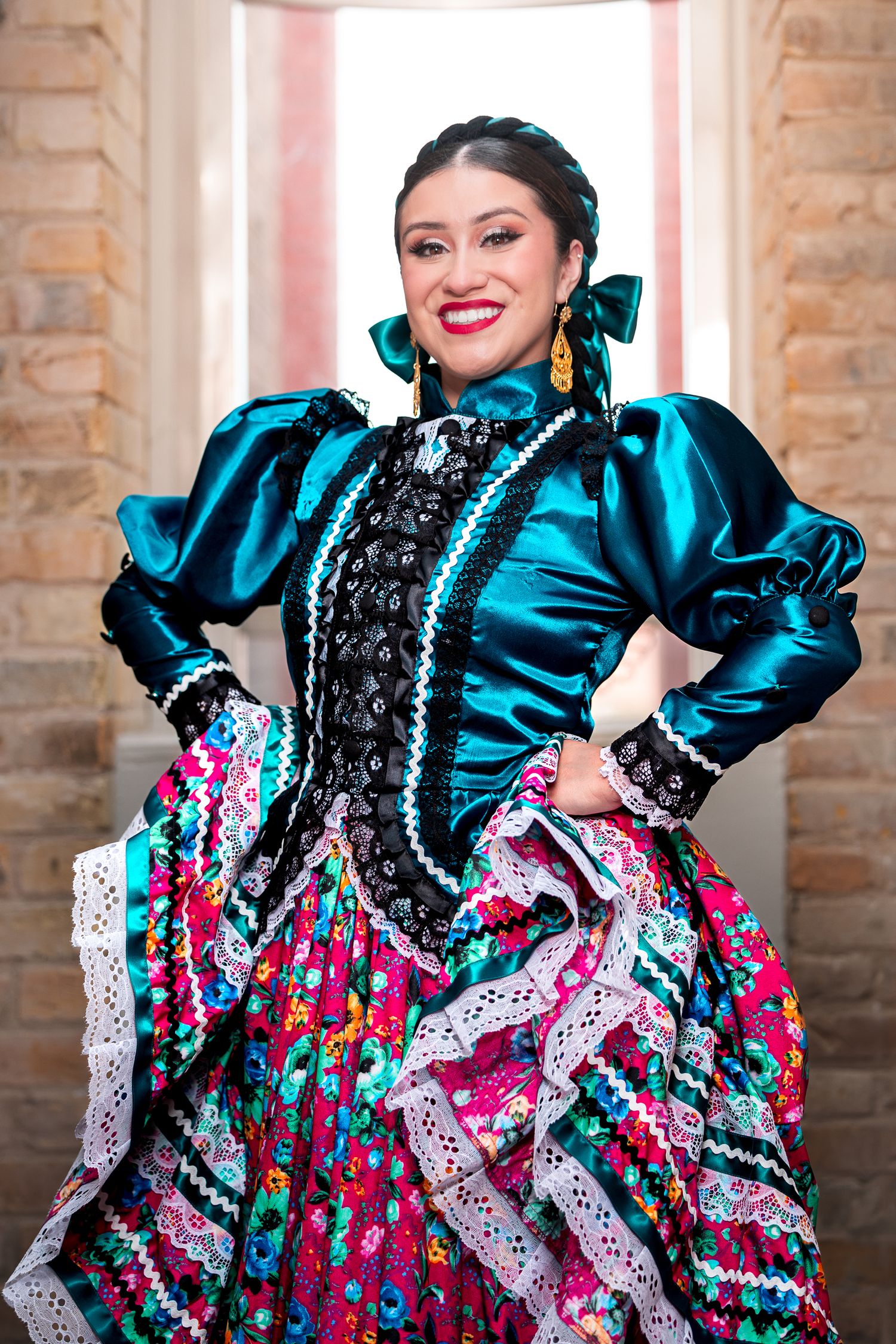 Traditional Mexican dancer in vibrant turquoise and floral dress performs with expressive movements and flowing ruffles.