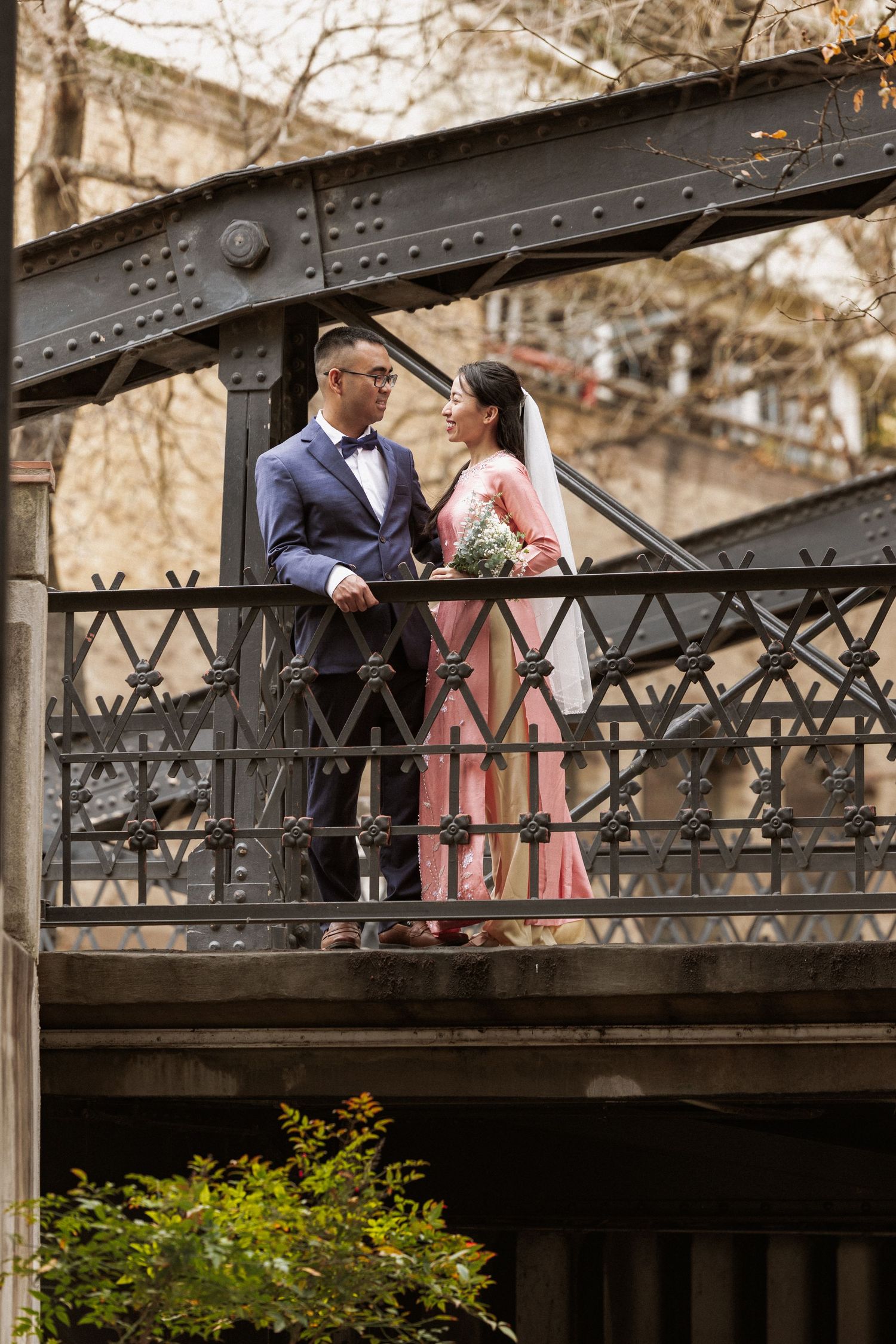 A couple shares an intimate moment on a vintage iron bridge during a photo session.