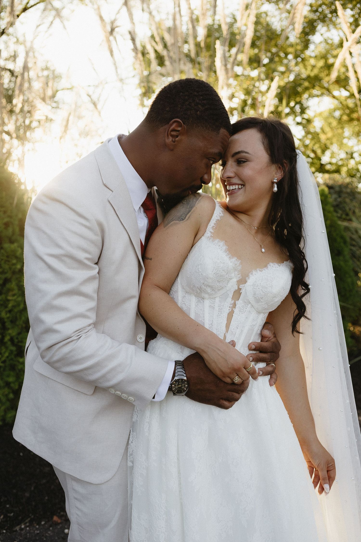 A romantic outdoor wedding photoshoot with a couple in white attire against a natural backdrop.