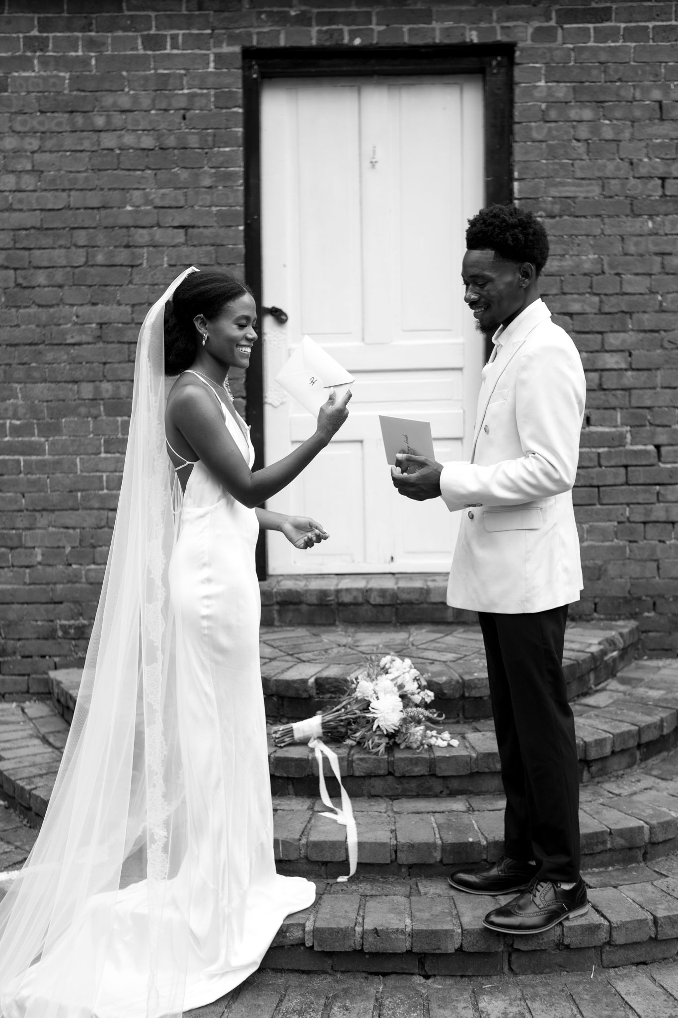 A series of five black and white photos showing a bride and father sharing a playful dance moment outside a brick building.