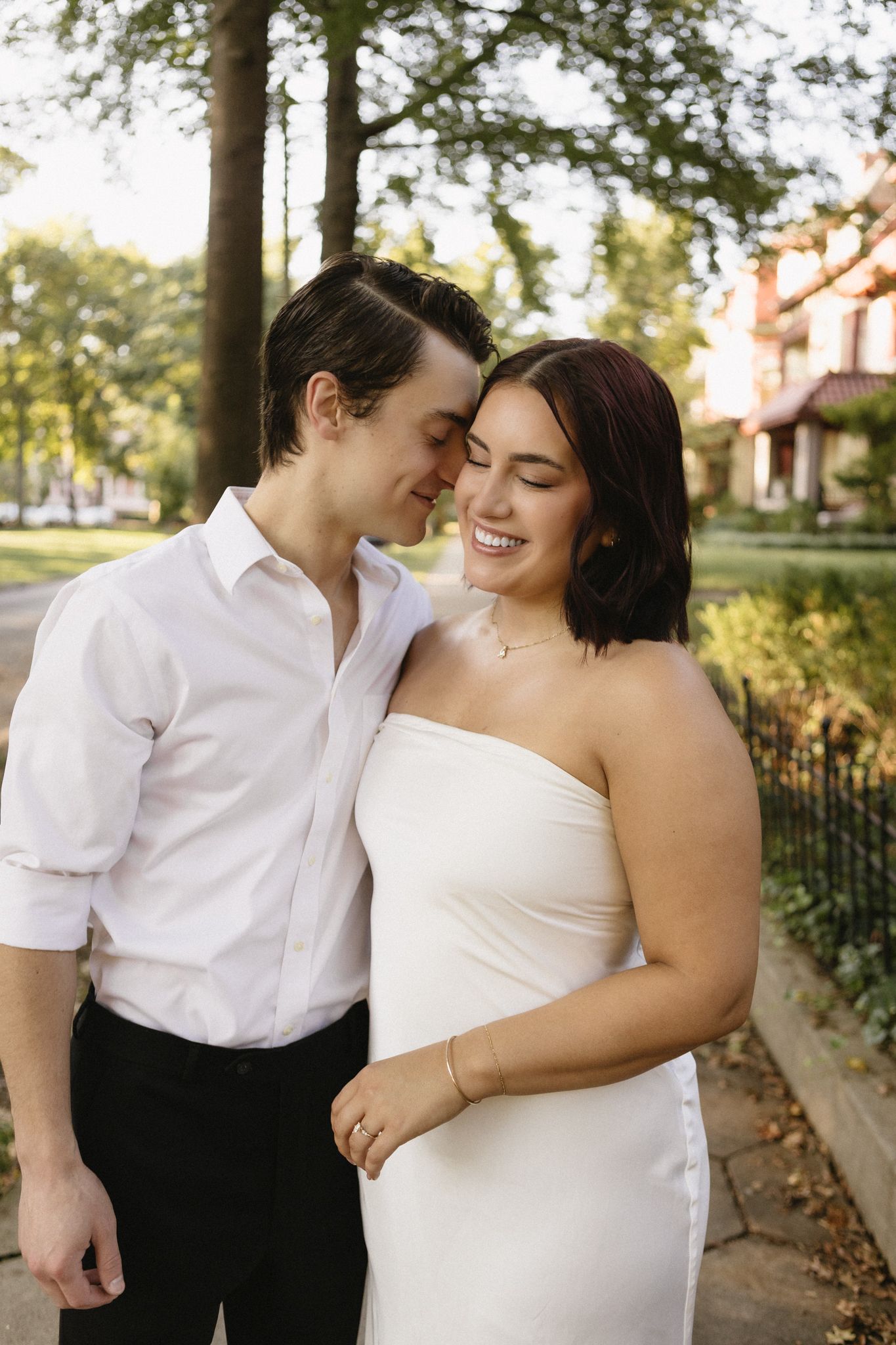 A couple shares intimate moments in a romantic outdoor photoshoot wearing white and black formal attire.