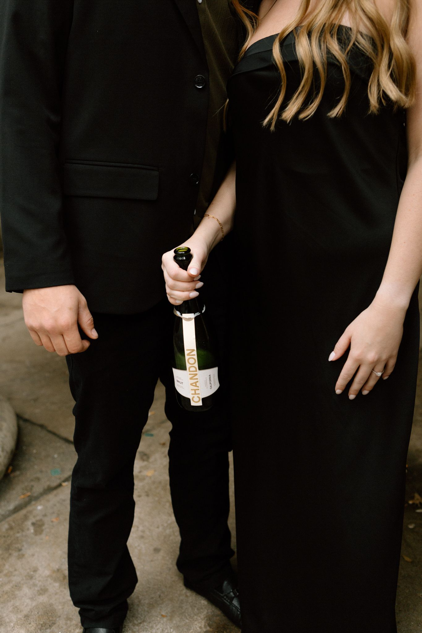 Engaged couple celebrating with a bottle of Chandon, sharing a joyful moment and laughter in downtown Louisville