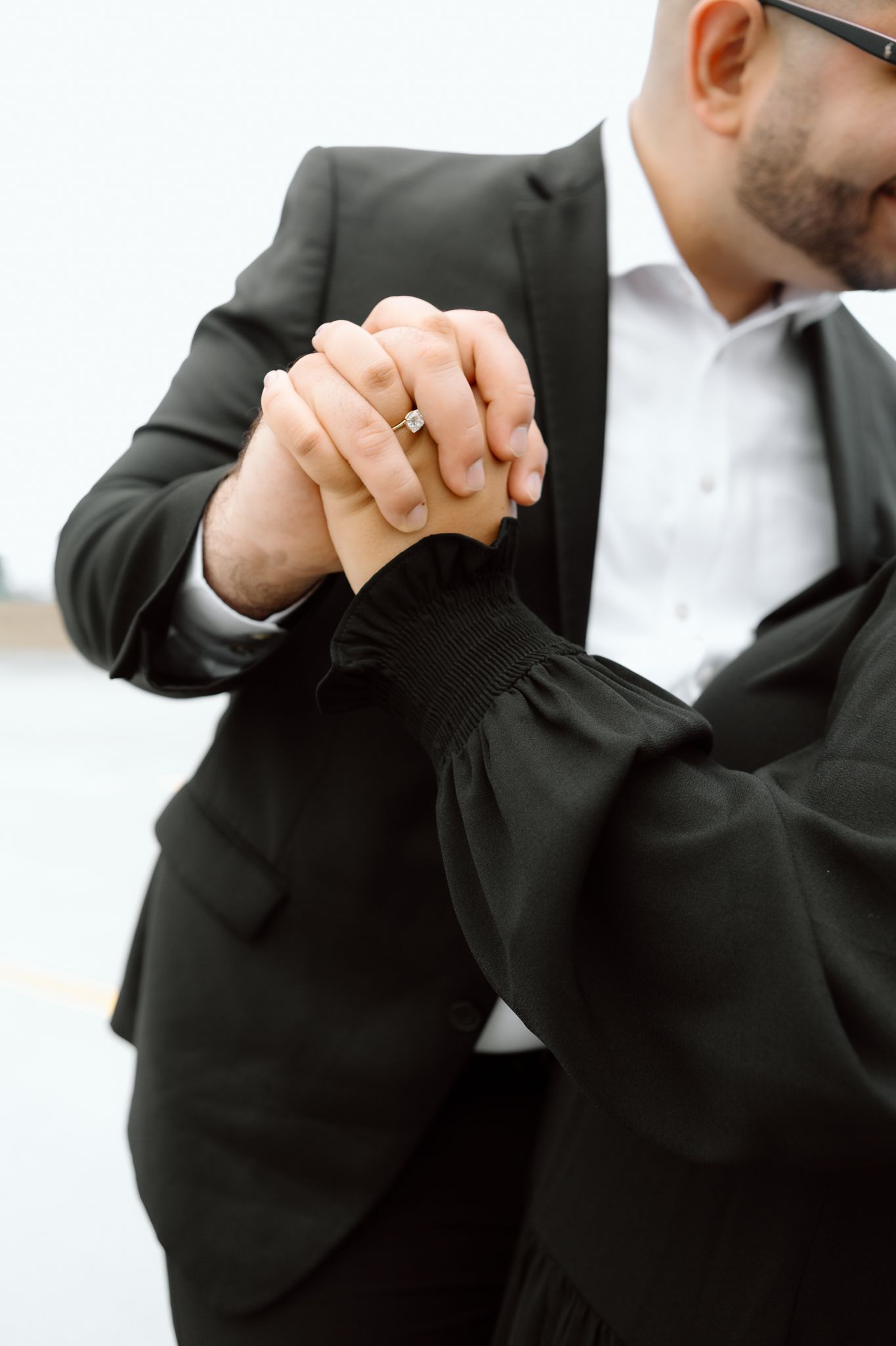 Engaged couple in downtown Louisville, with the woman smiling and showing her engagement ring while embracing her fiancé