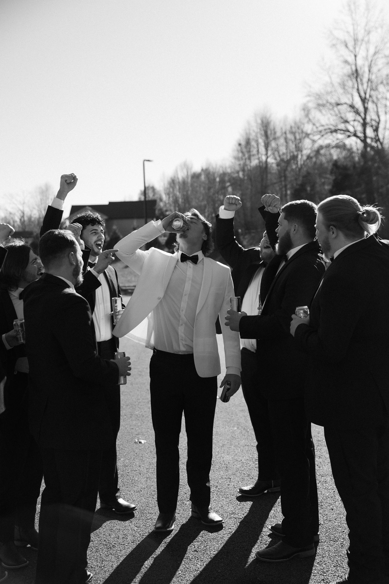 Black and white photo of wedding party members lined up outdoors in formal attire.