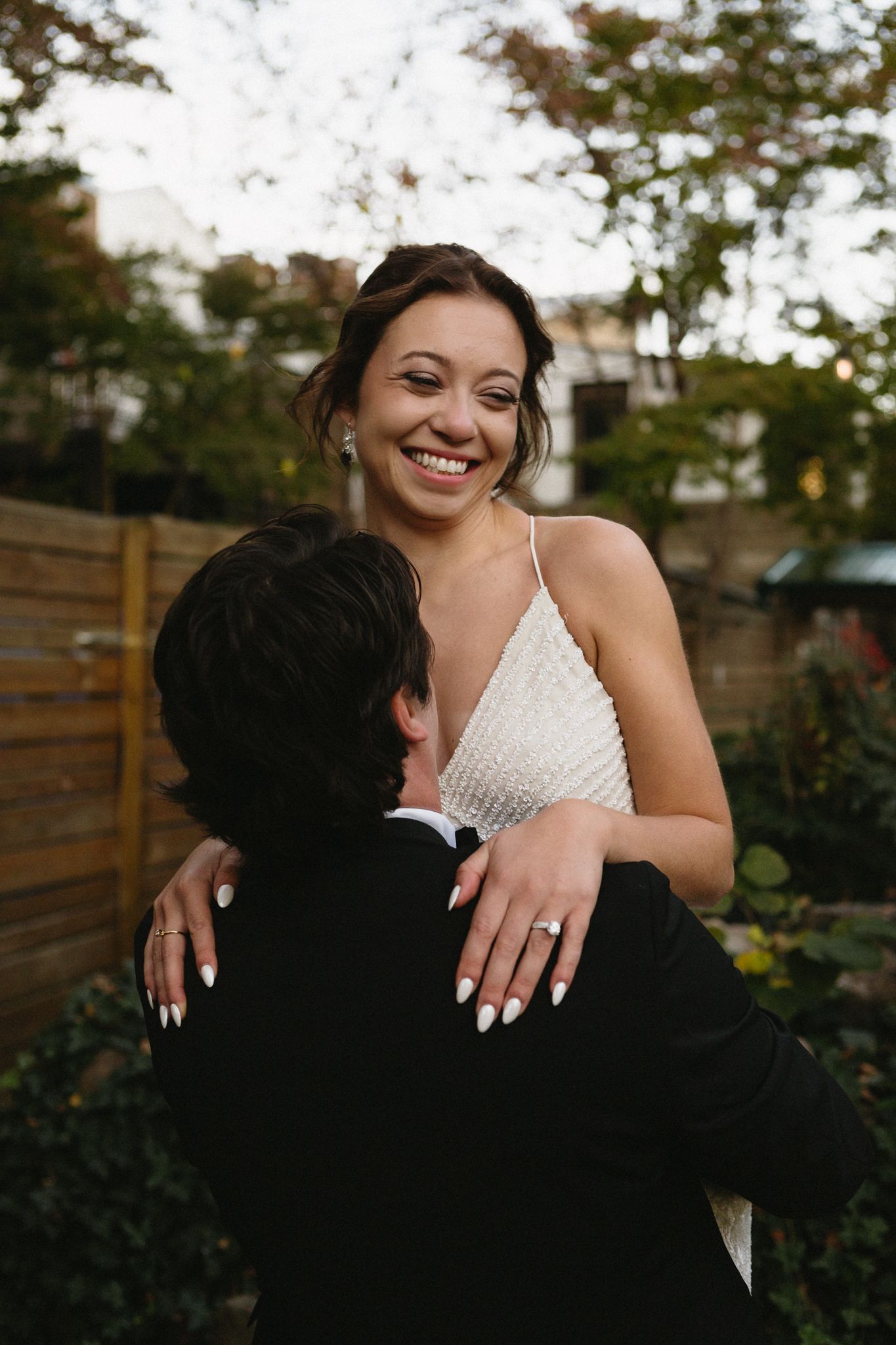 A couple shares a joyful embrace in an outdoor garden setting.