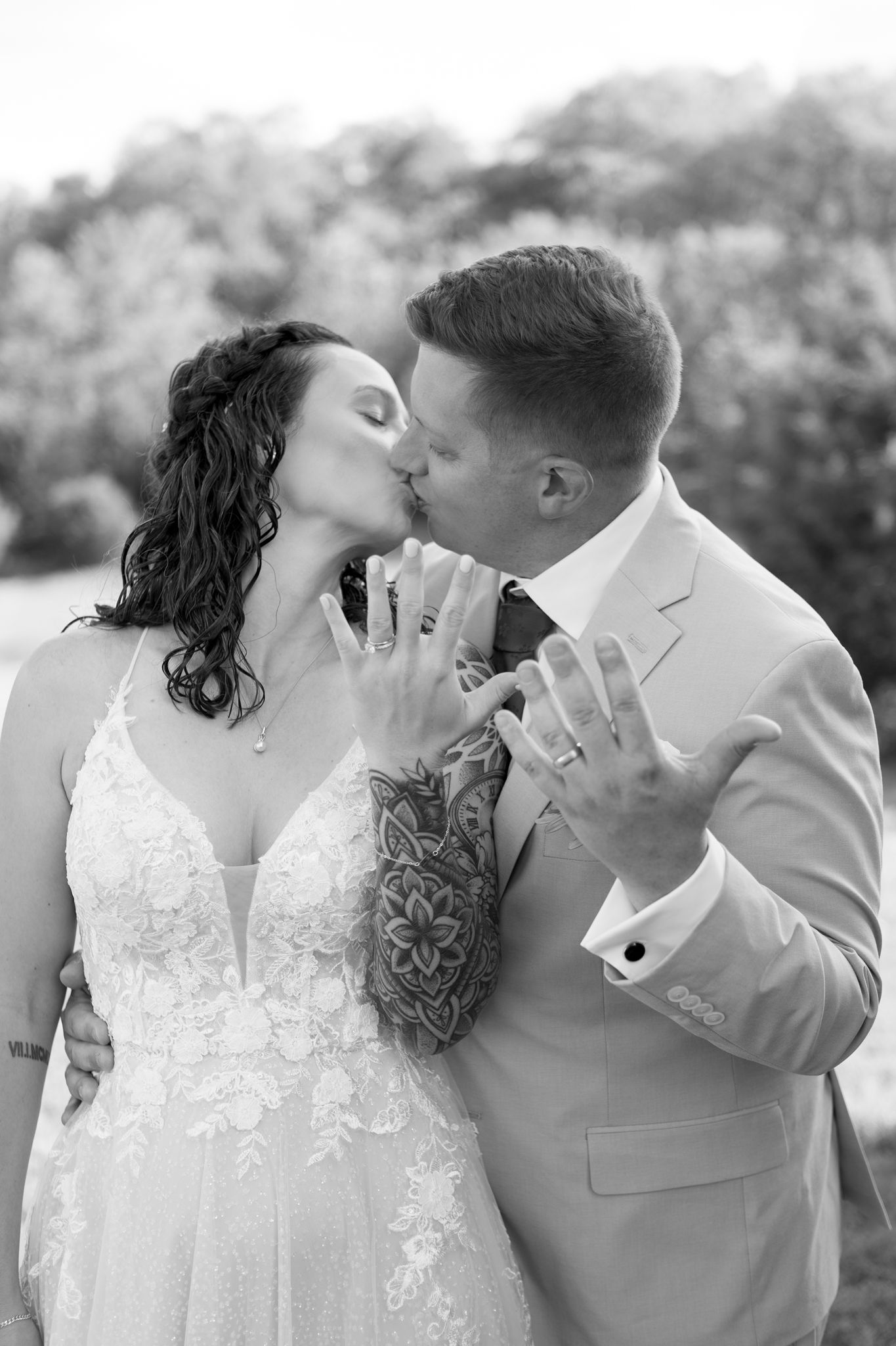 A black and white wedding photo capturing an intimate moment between newlyweds in elegant attire.