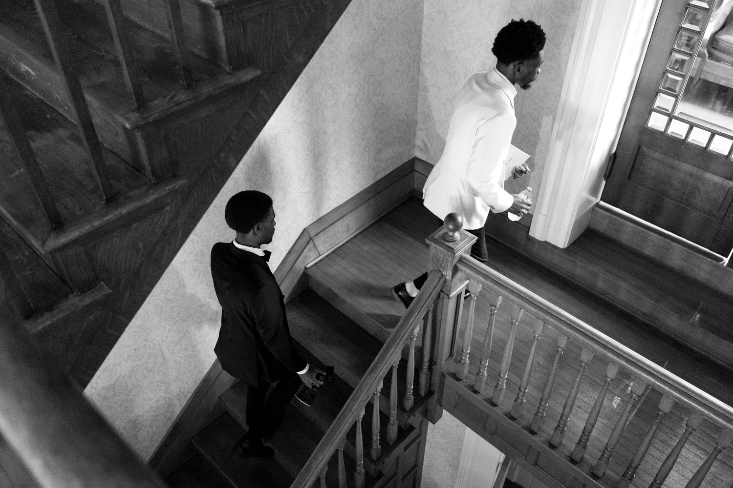 A haunting black and white sequence of figures moving on a dark staircase creates an eerie horror movie atmosphere.
